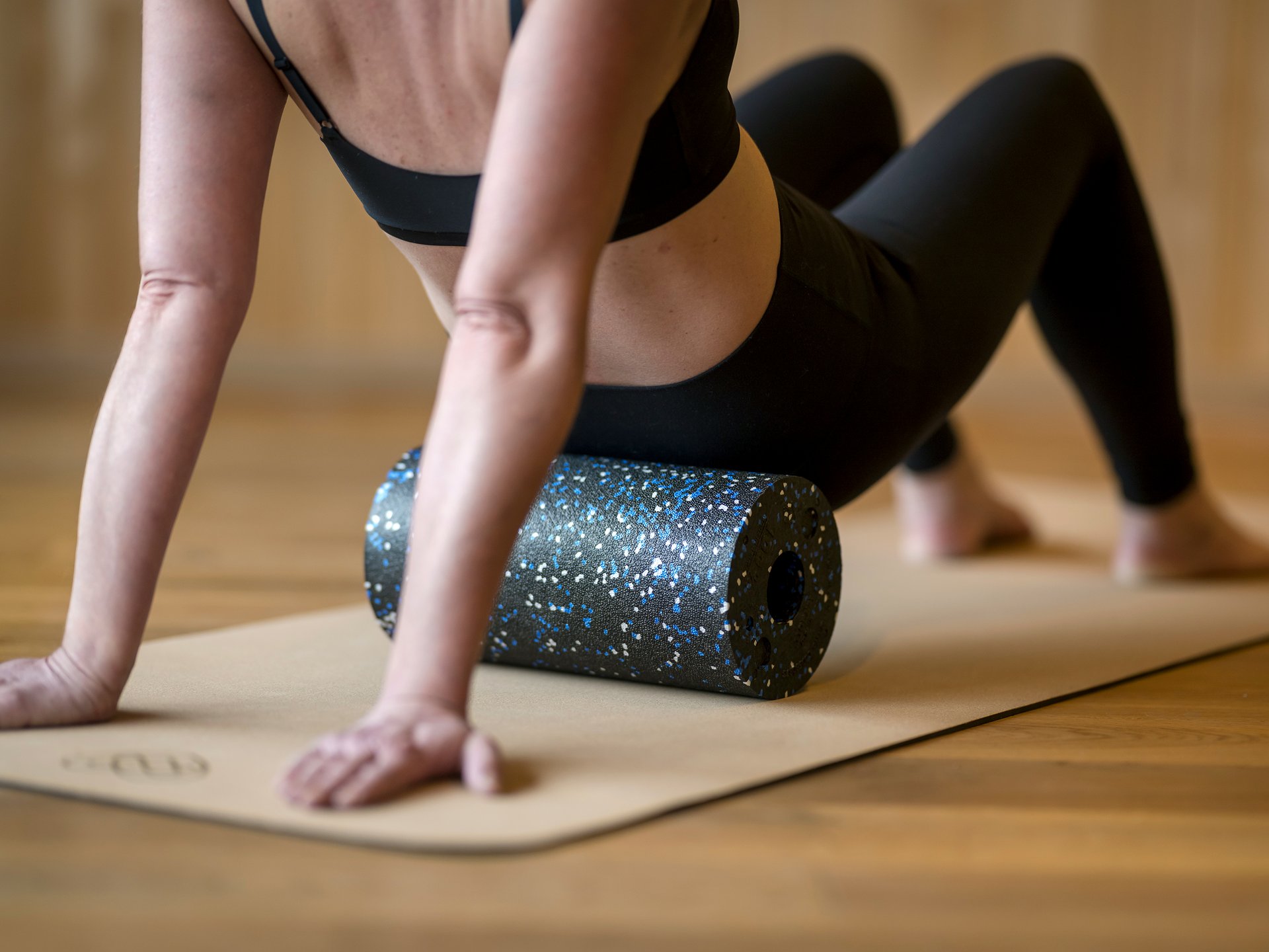 Seezeit re.connect – Bewusste Verbindung mit Natur & Kraftort Frau nutzt Schaumstoffrolle zur Muskelmassage auf Yoga-Matte