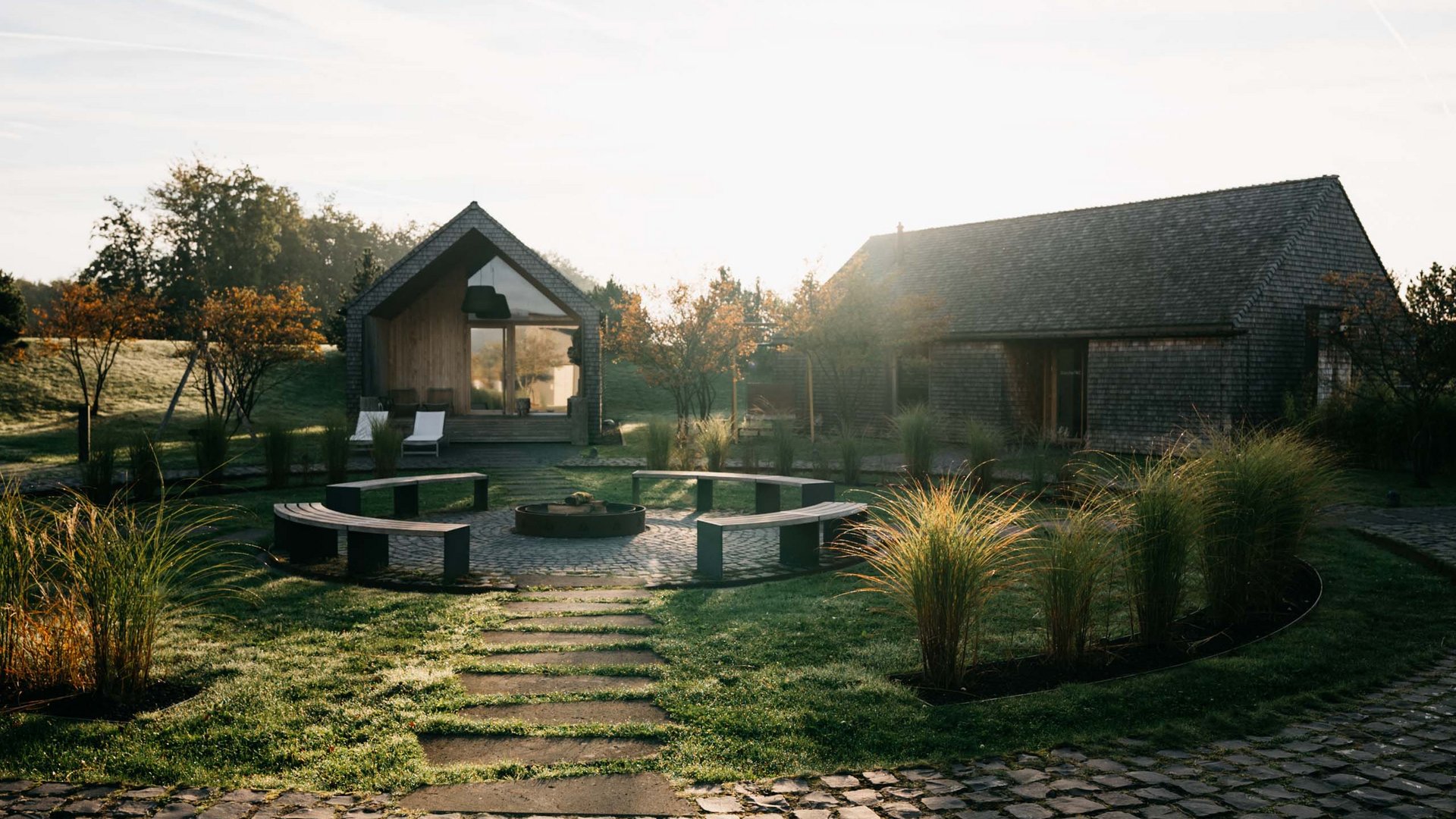 Ihr Kraftort in Deutschland Weg zu zwei Häusern mit Sitzbereich und Garten in der Morgensonne