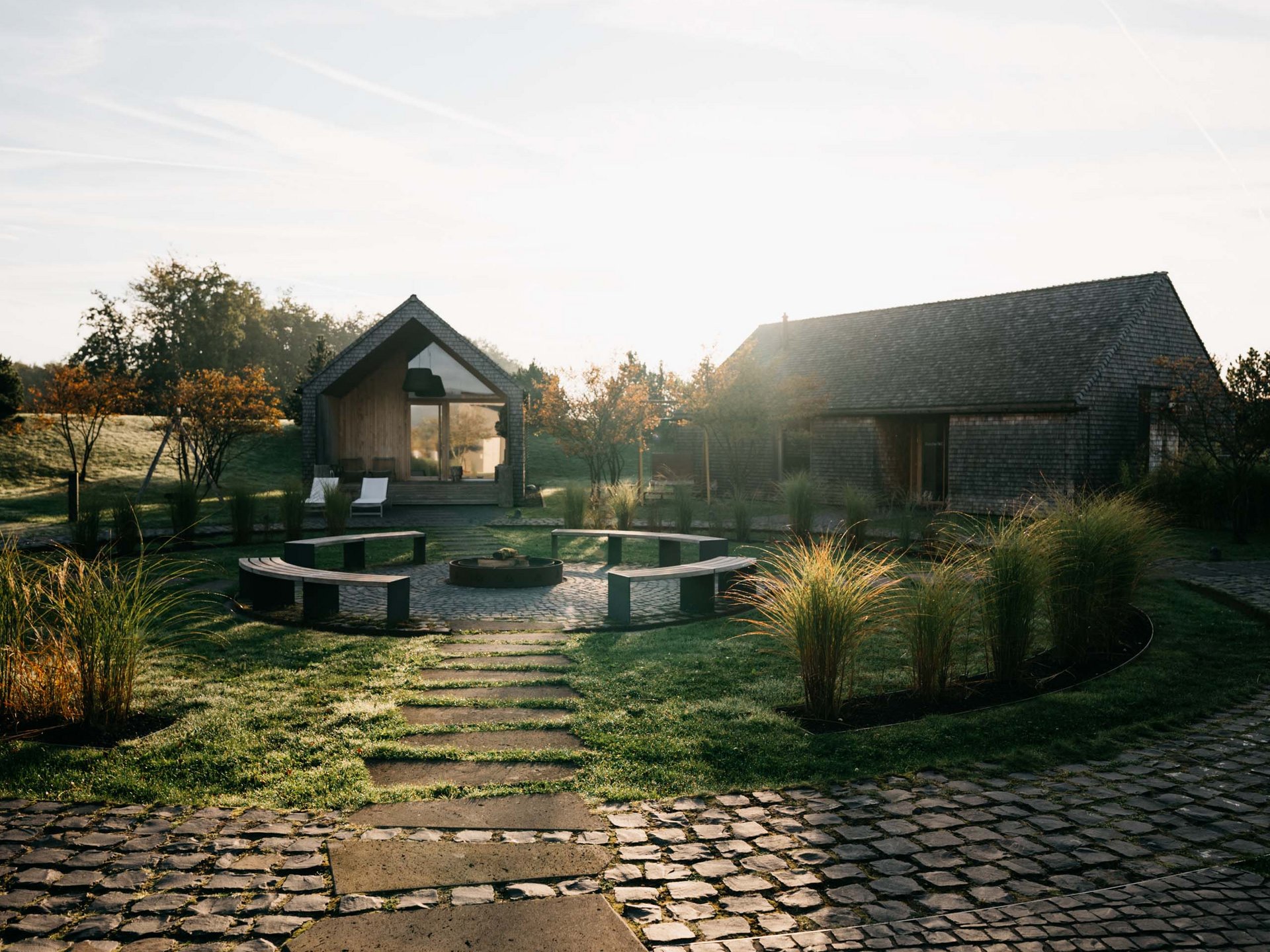 Le Seezeitlodge : votre hôtel au lac de Bostal Sentier menant à deux maisons avec espace de détente et jardin au lever du soleil