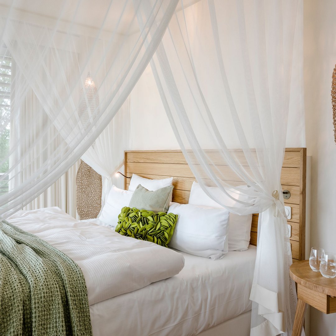 Seezeitlodge : protection des données Lit confortable avec cadre en bois, rideaux blancs et coussin vert dans une chambre d'hôtel