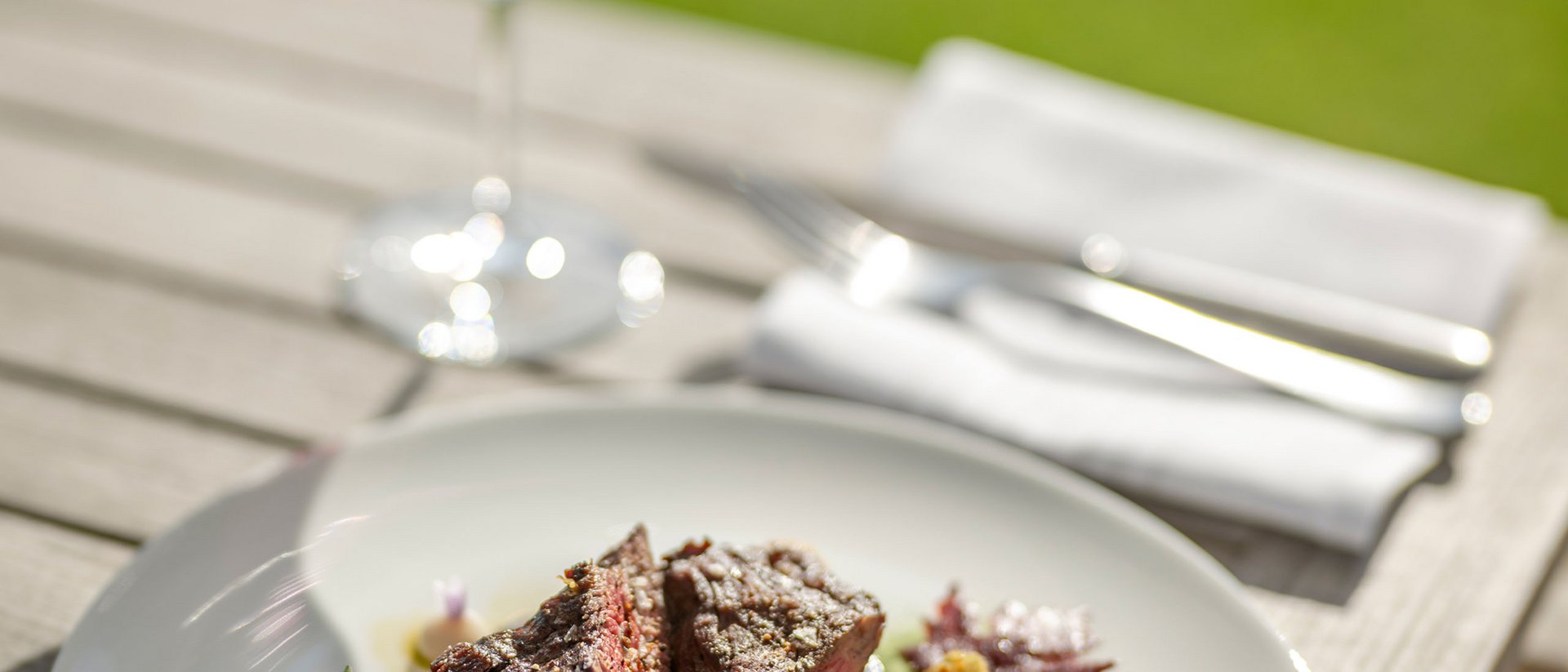 Seezeitlodge: Bildergalerie Steak mit Gemüse auf weißem Teller und Glas Rotwein im Freien