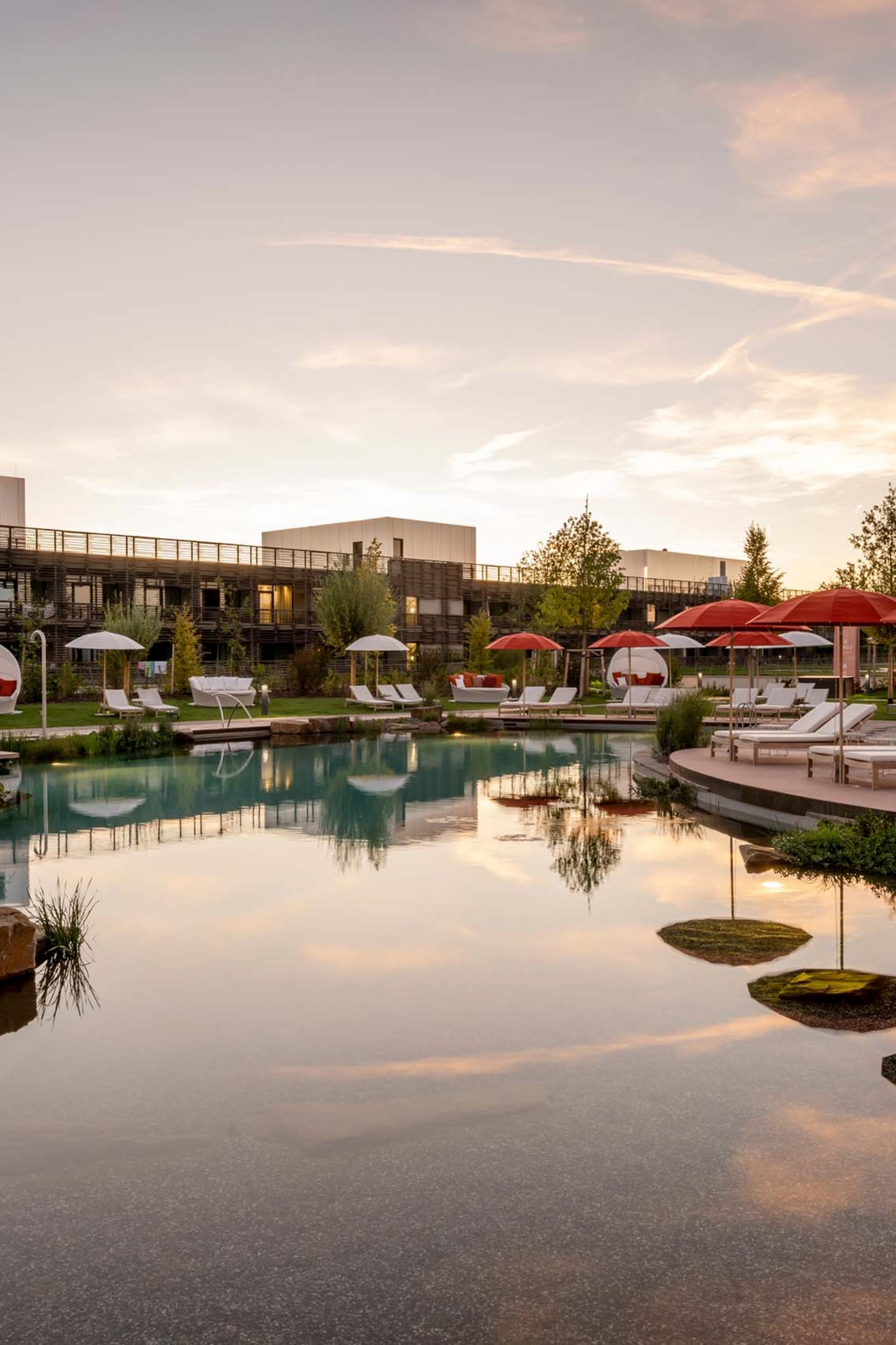 Seezeitlodge : Galerie photos Piscine d'hôtel avec chaises longues et parasols rouges au coucher du soleil