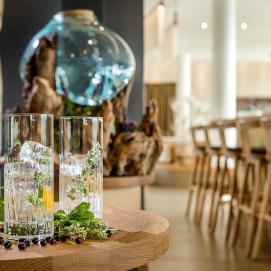 Ihr Genusshotel am Bostalsee Zwei Gläser mit Eis und Kräutern auf einem Holztisch in einer Bar