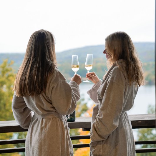 Seezeitlodge : Day Spa au bord du lac de Bostal Deux femmes en peignoirs trinquent avec des verres de vin sur une terrasse