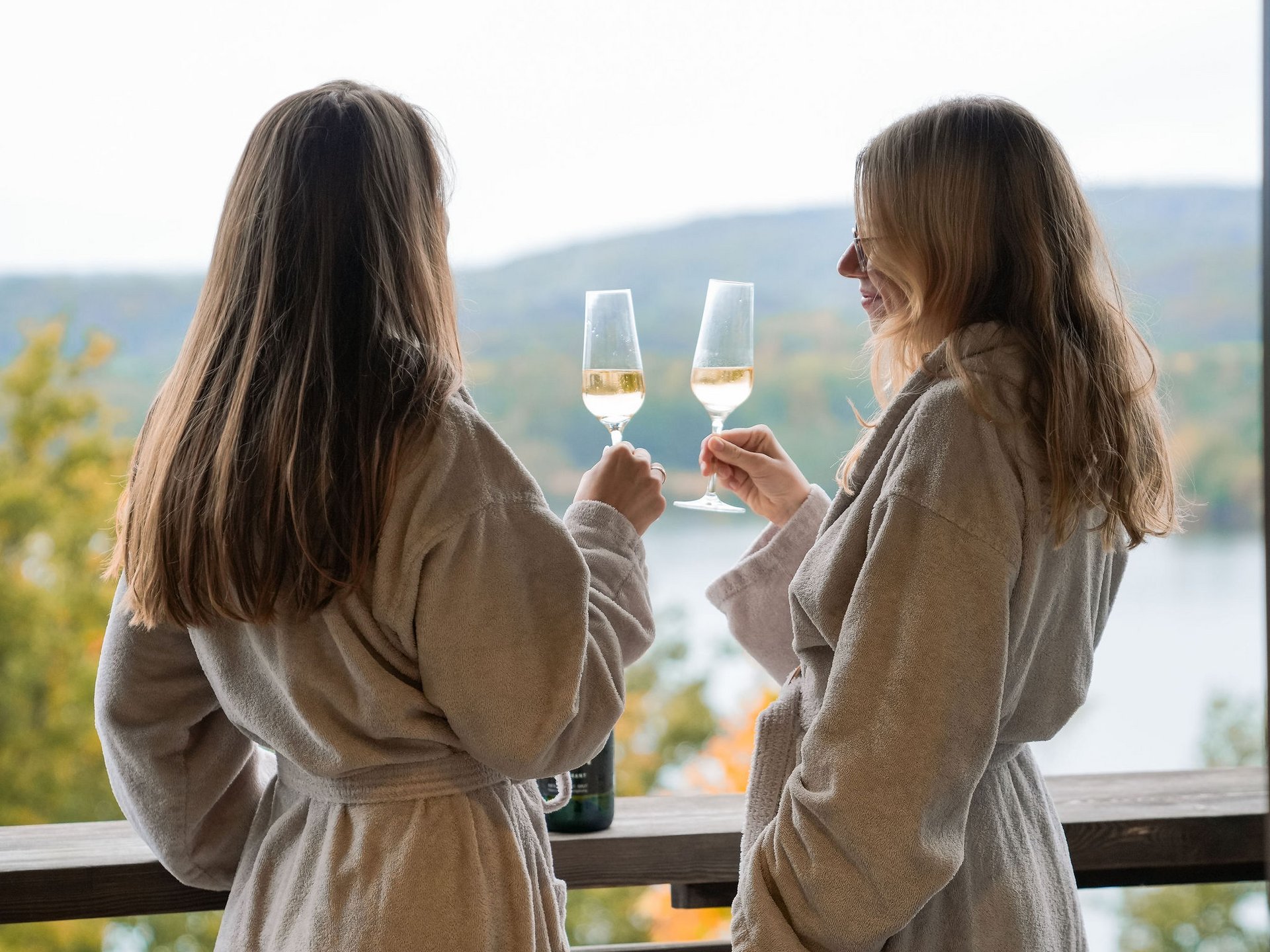 Le Seezeitlodge : votre hôtel au lac de Bostal Deux femmes en peignoirs trinquent avec des verres de vin sur une terrasse