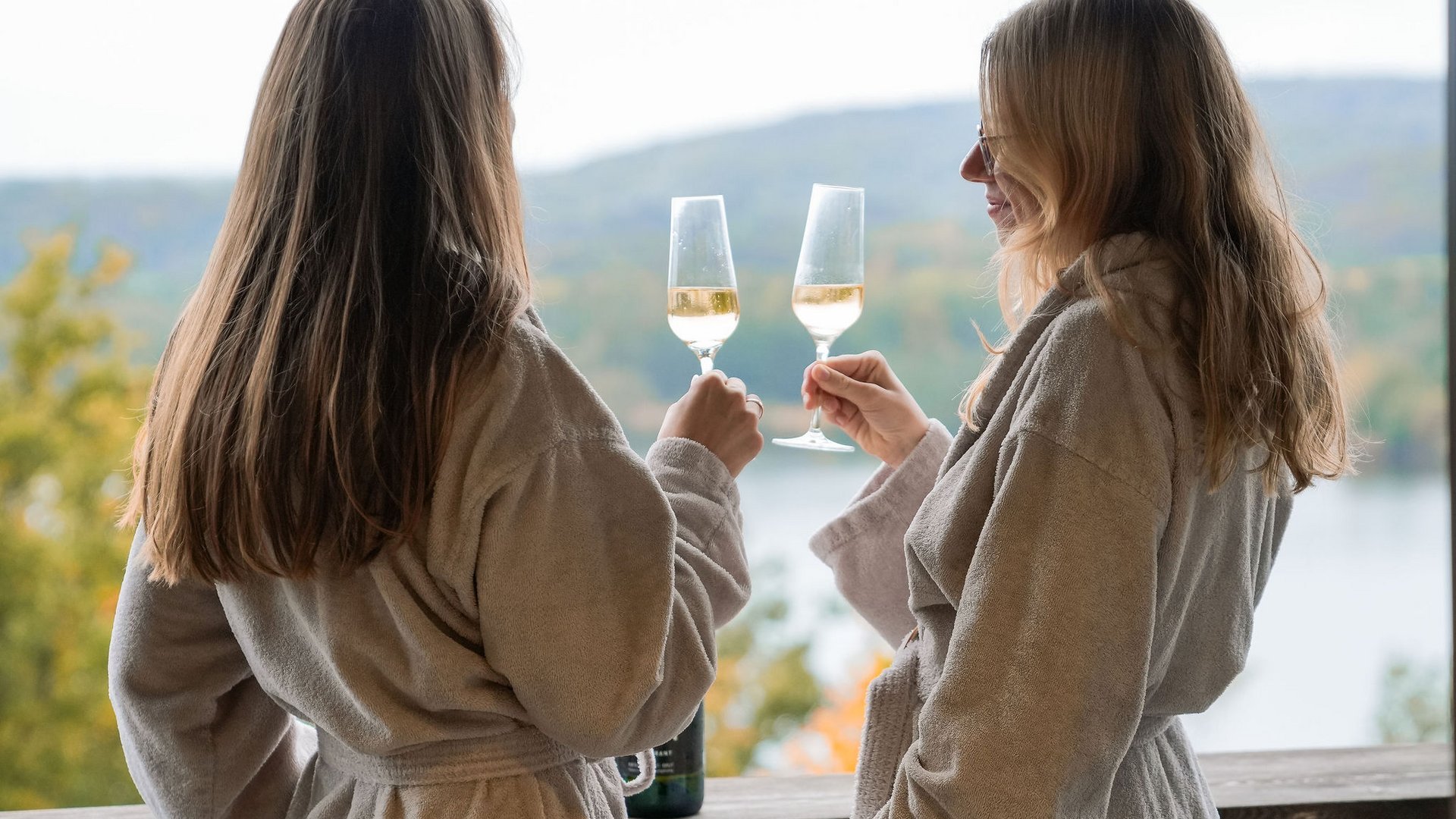 Seezeitlodge : Galerie photos Deux femmes en peignoirs trinquent avec des verres de vin sur une terrasse