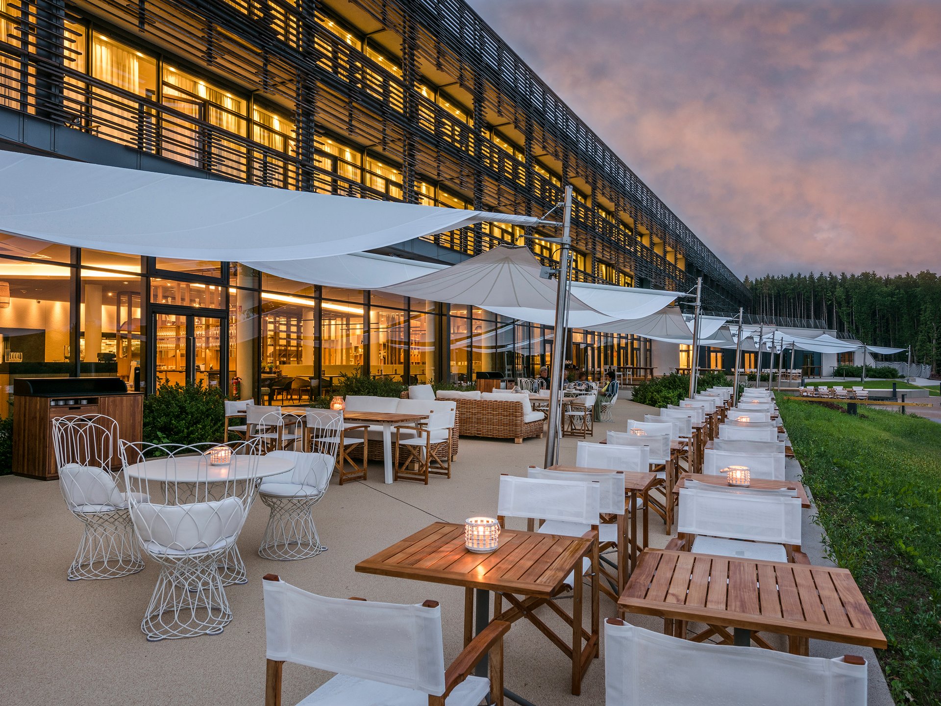Design hotel Germany: your retreat at Lake Bostalsee Outdoor terrace of a modern restaurant with lit tables at sunset