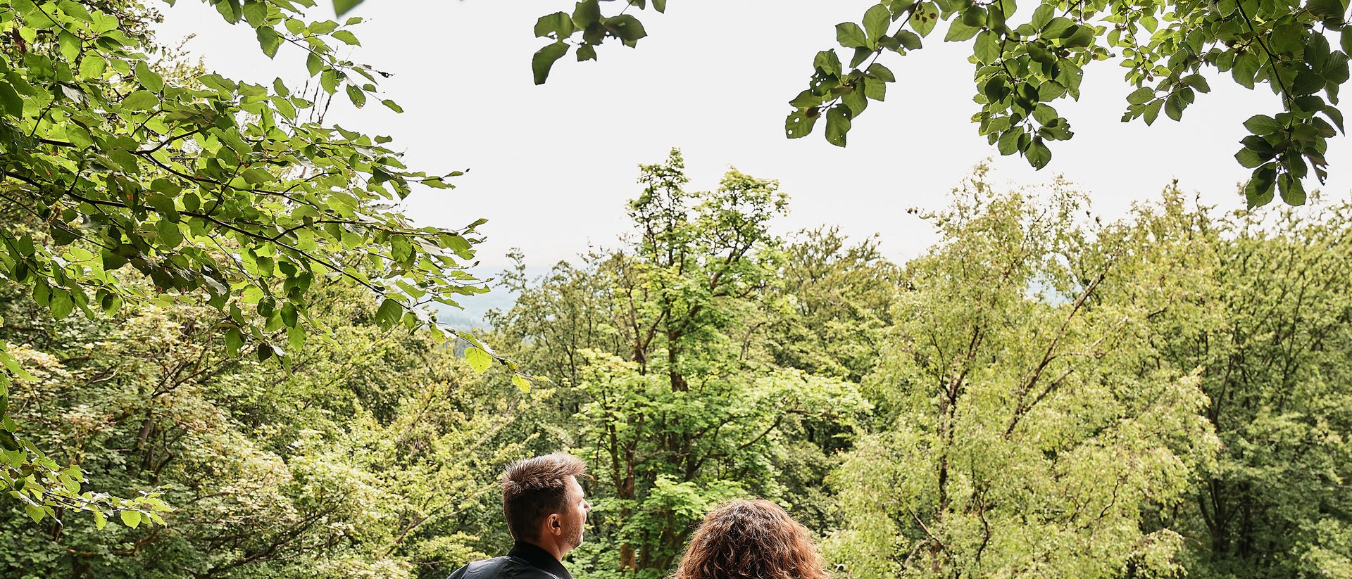 Seezeitlodge: Bildergalerie Paar steht im Wald und blickt auf Bäume und Natur