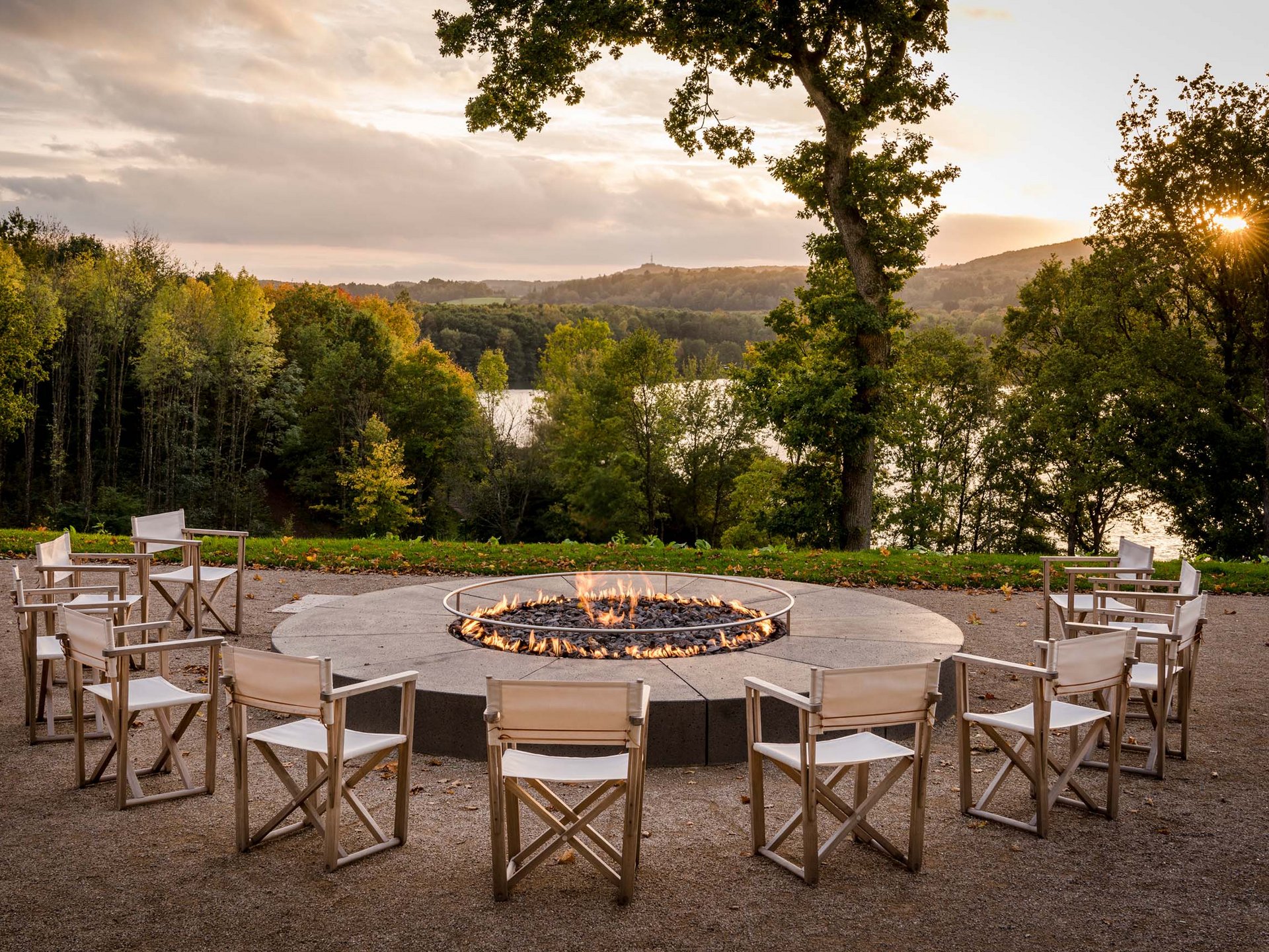 Le Seezeitlodge : votre hôtel au lac de Bostal Foyer extérieur avec des chaises en cercle devant forêt et lac au coucher du soleil