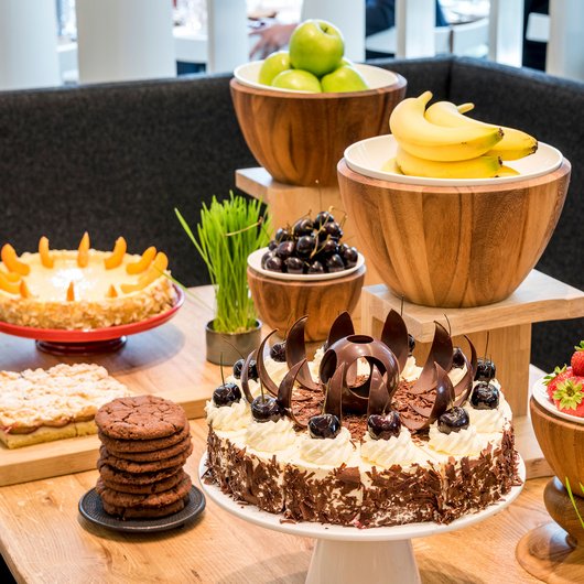 Echter Genuss am Bostalsee Tisch mit verschiedenen Kuchen, Keksen und frischem Obst in Holzschalen
