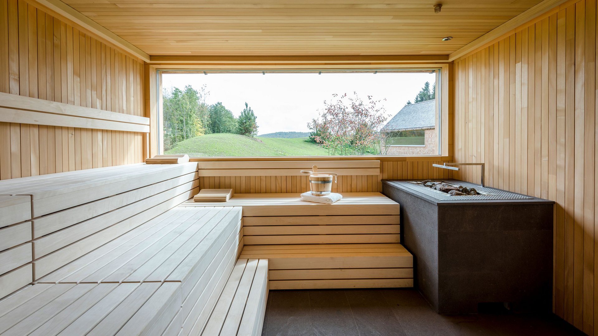 Seezeitlodge : Galerie photos Salle de sauna en bois moderne avec grande fenêtre donnant sur paysage