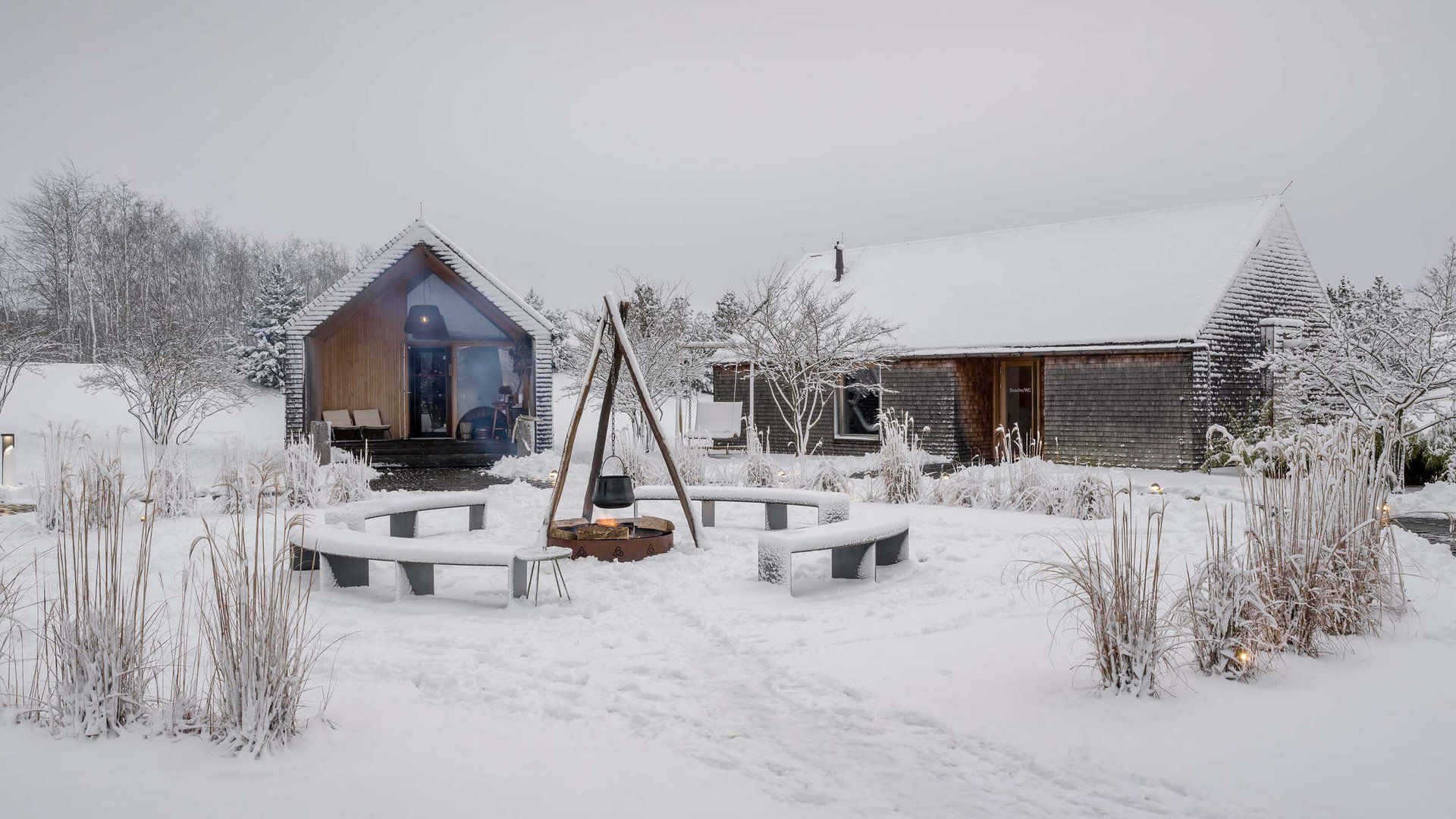 Die Seezeitlodge: Ihr Hotel am Bostalsee Verschneite Holzhäuser mit Feuerstelle und runden Sitzbänken im Wintergarten