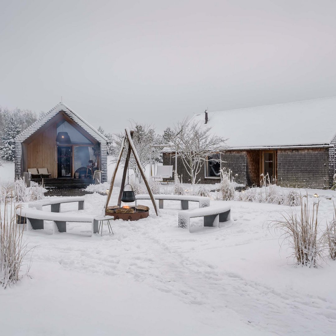 Die Seezeitlodge: Ihr Hotel am Bostalsee Verschneite Holzhäuser mit Feuerstelle und runden Sitzbänken im Wintergarten
