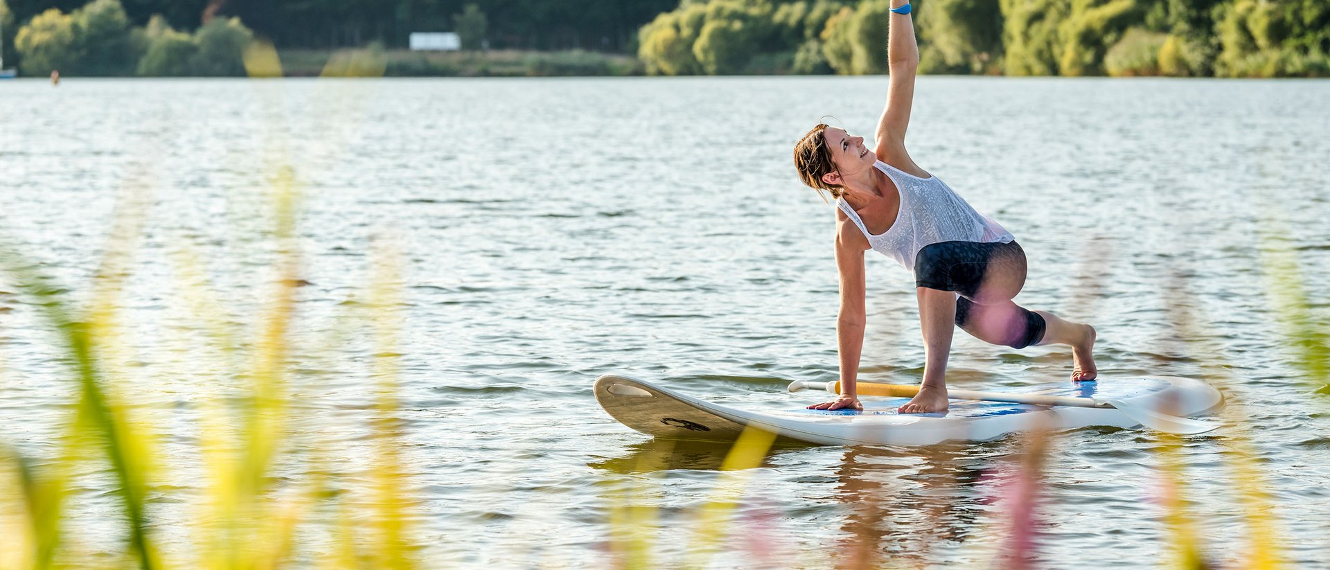 Seezeitlodge : Galerie photos Femme pratiquant le yoga sur une planche de paddle sur un lac
