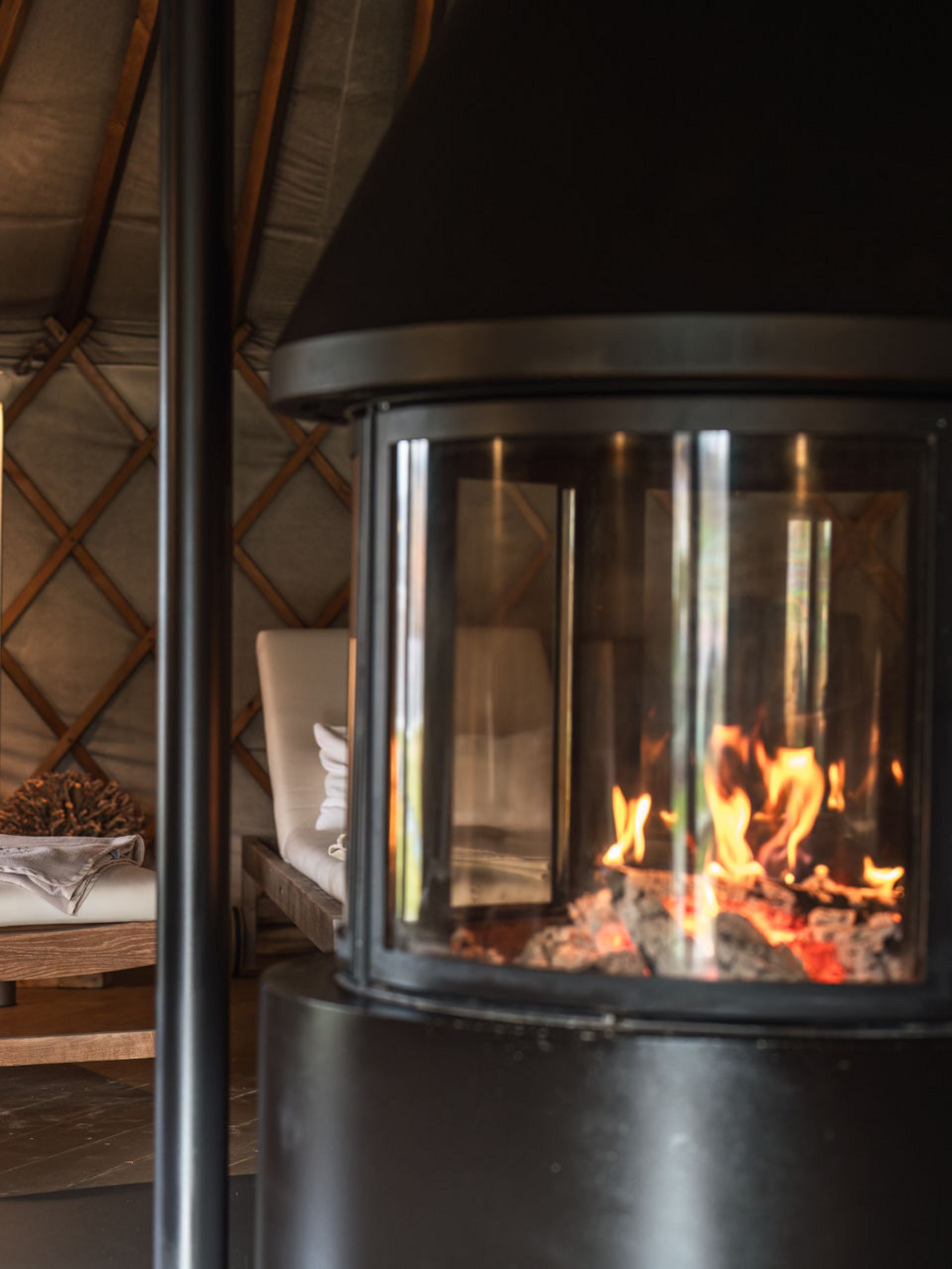 Seezeitlodge: Bildergalerie Flackerndes Feuer im Kamin und gepolsterte Holzliegen in gemütlichem Raum