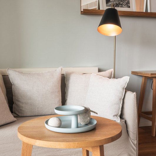 Übernachten am Bostalsee: Seezeitlodge Hotel & Spa Beleuchtete Stehlampe neben Sofa mit Kissen und Holzbeistelltisch