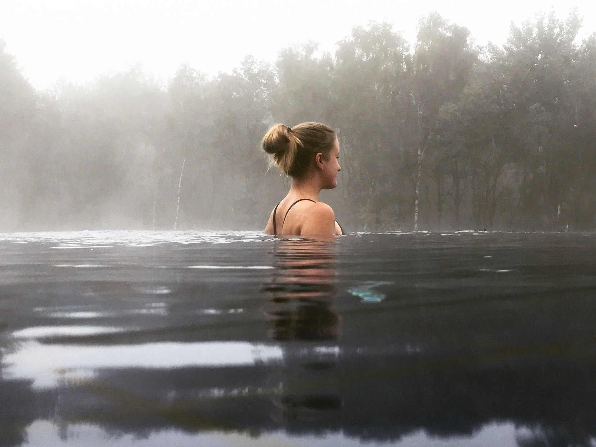 Seezeitlodge : Day Spa au bord du lac de Bostal Femme se détendant dans l'eau avec brouillard et arbres en arrière-plan