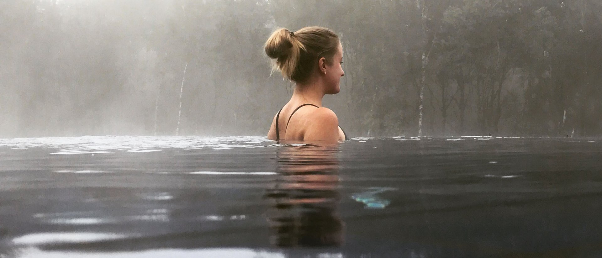 Seezeitlodge: Bildergalerie Frau entspannt im Wasser mit Nebel und Bäumen im Hintergrund