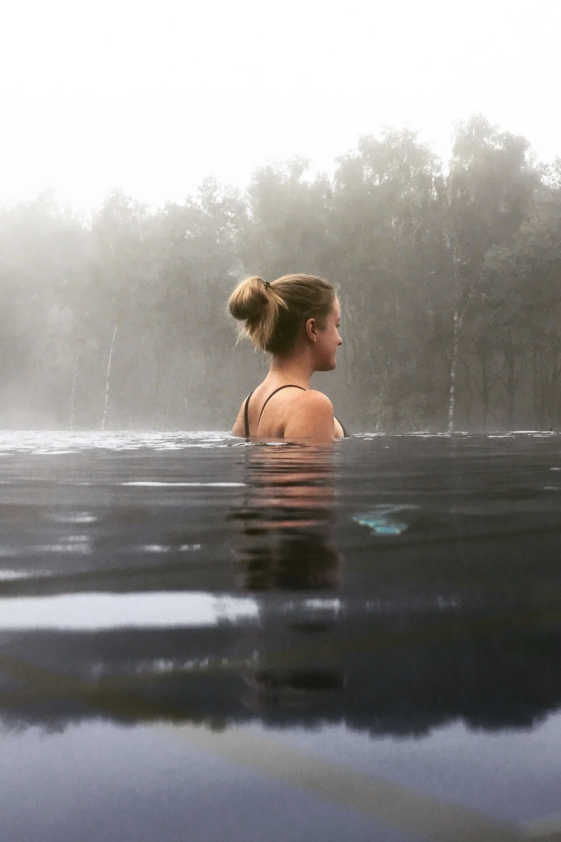 Seezeitlodge: Bildergalerie Frau entspannt im Wasser mit Nebel und Bäumen im Hintergrund