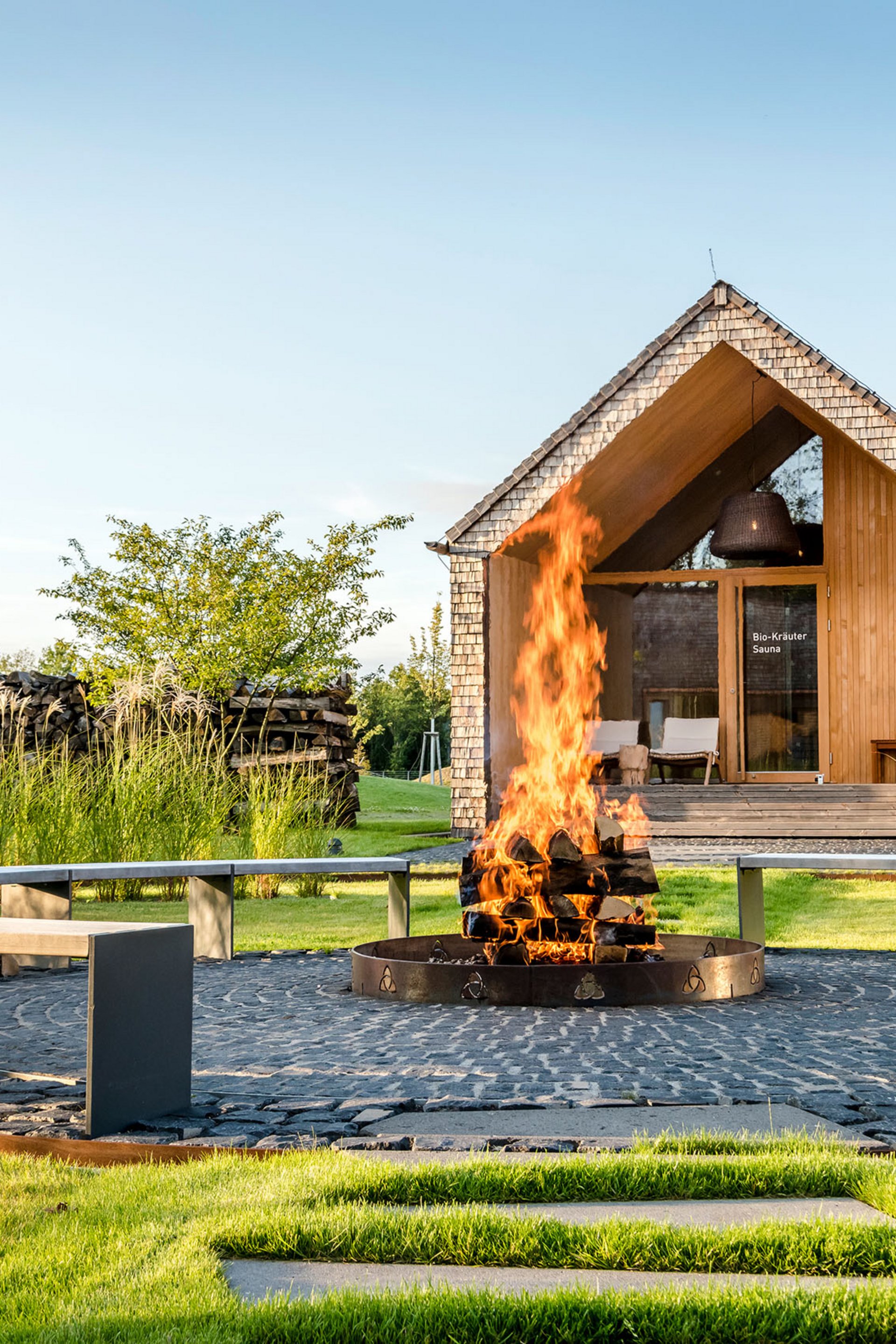 Seezeitlodge : Galerie photos Foyer avec bois en feu et banc circulaire devant un sauna en bois