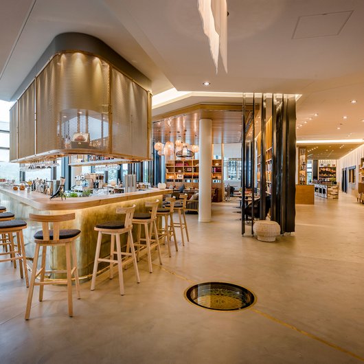 Ihr Genusshotel am Bostalsee Moderner heller Barbereich mit Holzstühlen und großen Fenstern