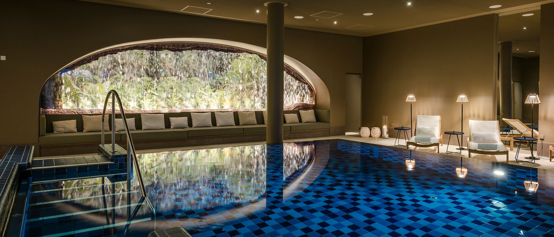 Seezeitlodge : Galerie photos Piscine intérieure chauffée avec cascade et fauteuils lounge éclairés chaleureusement