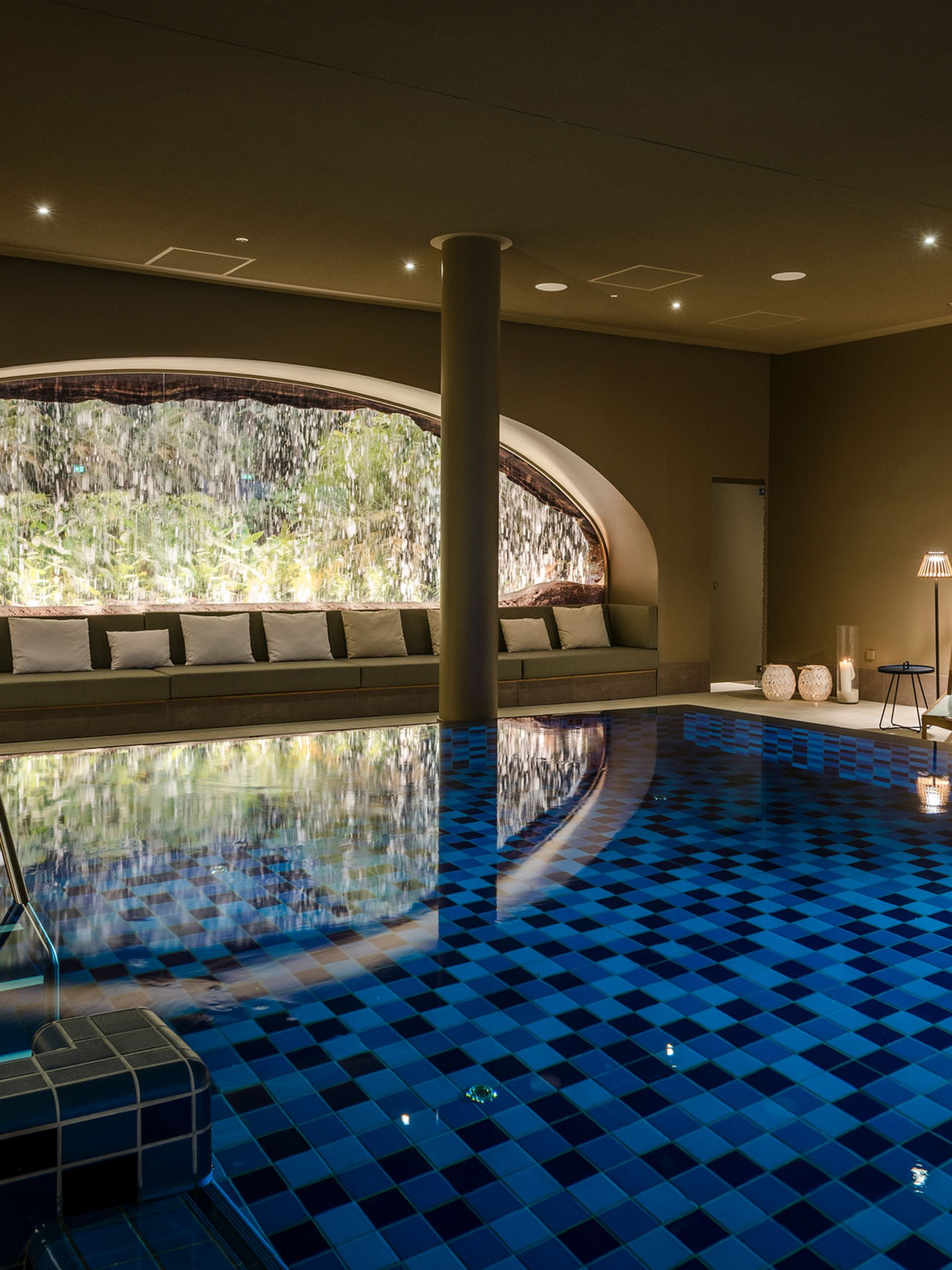 Seezeitlodge : Galerie photos Piscine intérieure chauffée avec cascade et fauteuils lounge éclairés chaleureusement