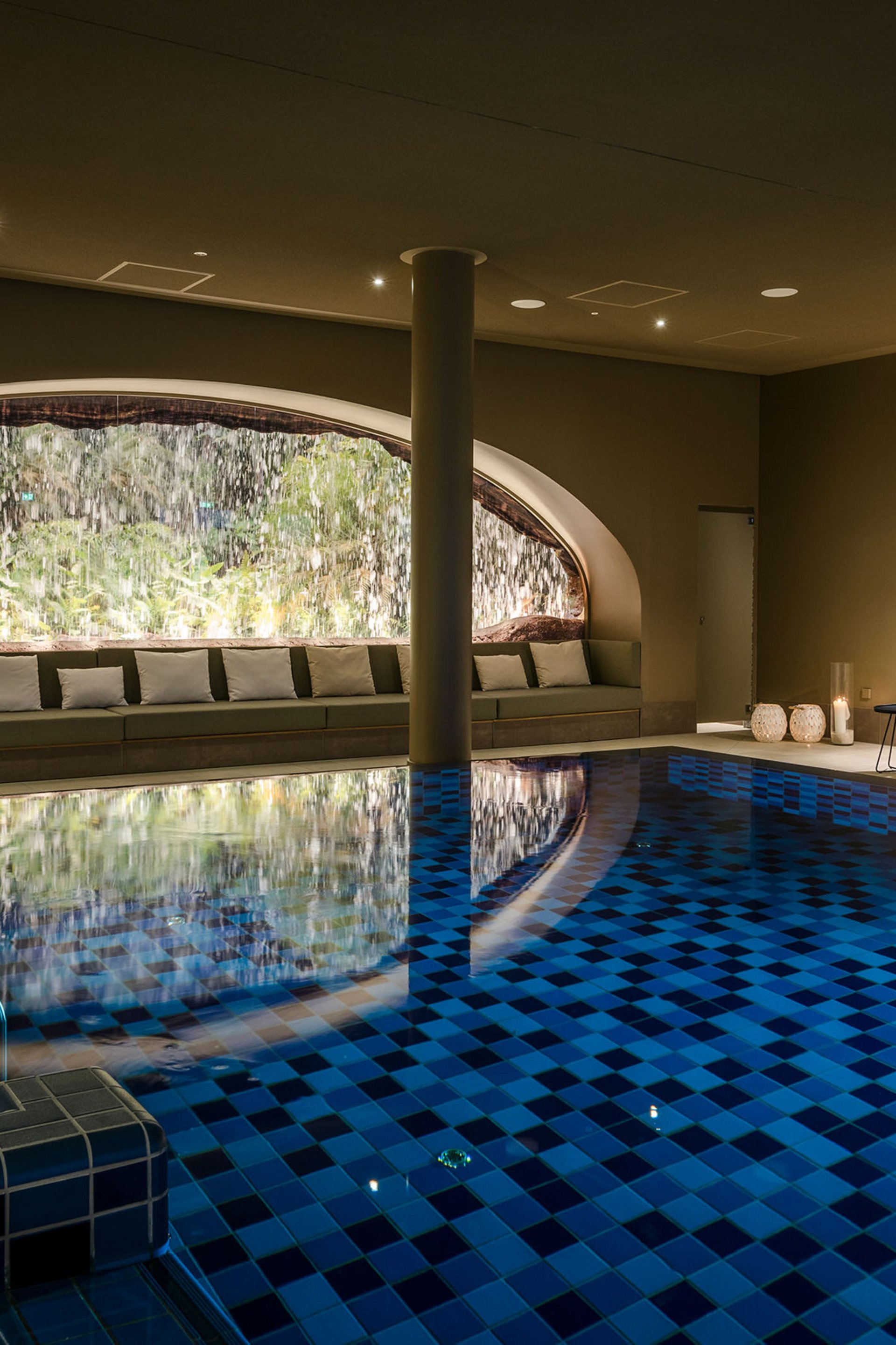 Seezeitlodge : Galerie photos Piscine intérieure chauffée avec cascade et fauteuils lounge éclairés chaleureusement