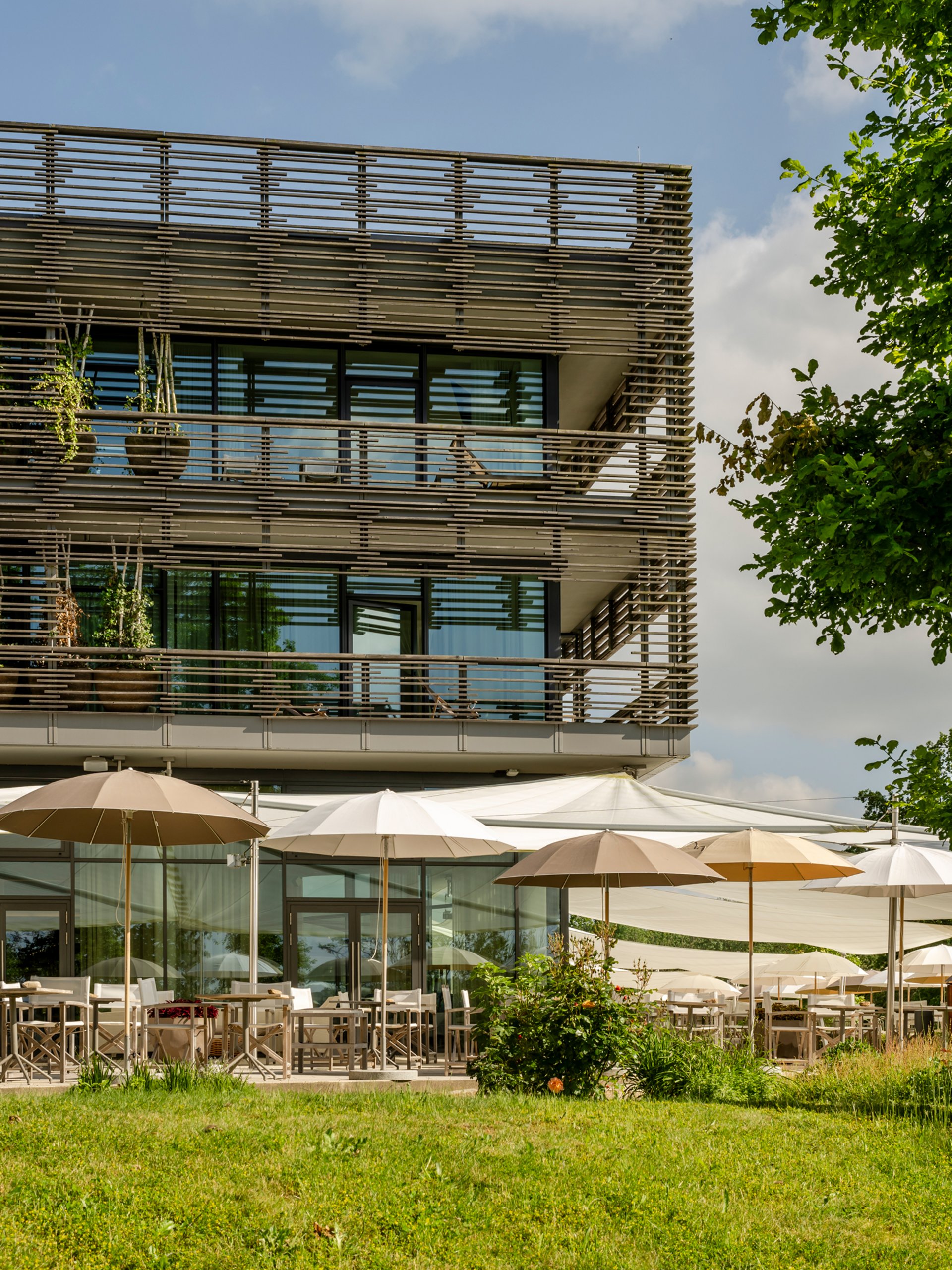 Seezeitlodge : Galerie photos Bâtiment moderne avec terrasse et parasols dans un espace vert