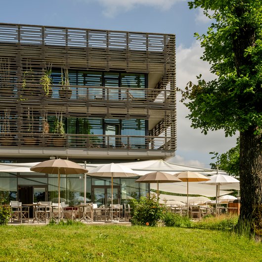 Luxushotel Seezeitlodge: Lassen Sie sich begeistern! Modernes Gebäude mit Terrasse und Sonnenschirmen im Grünen