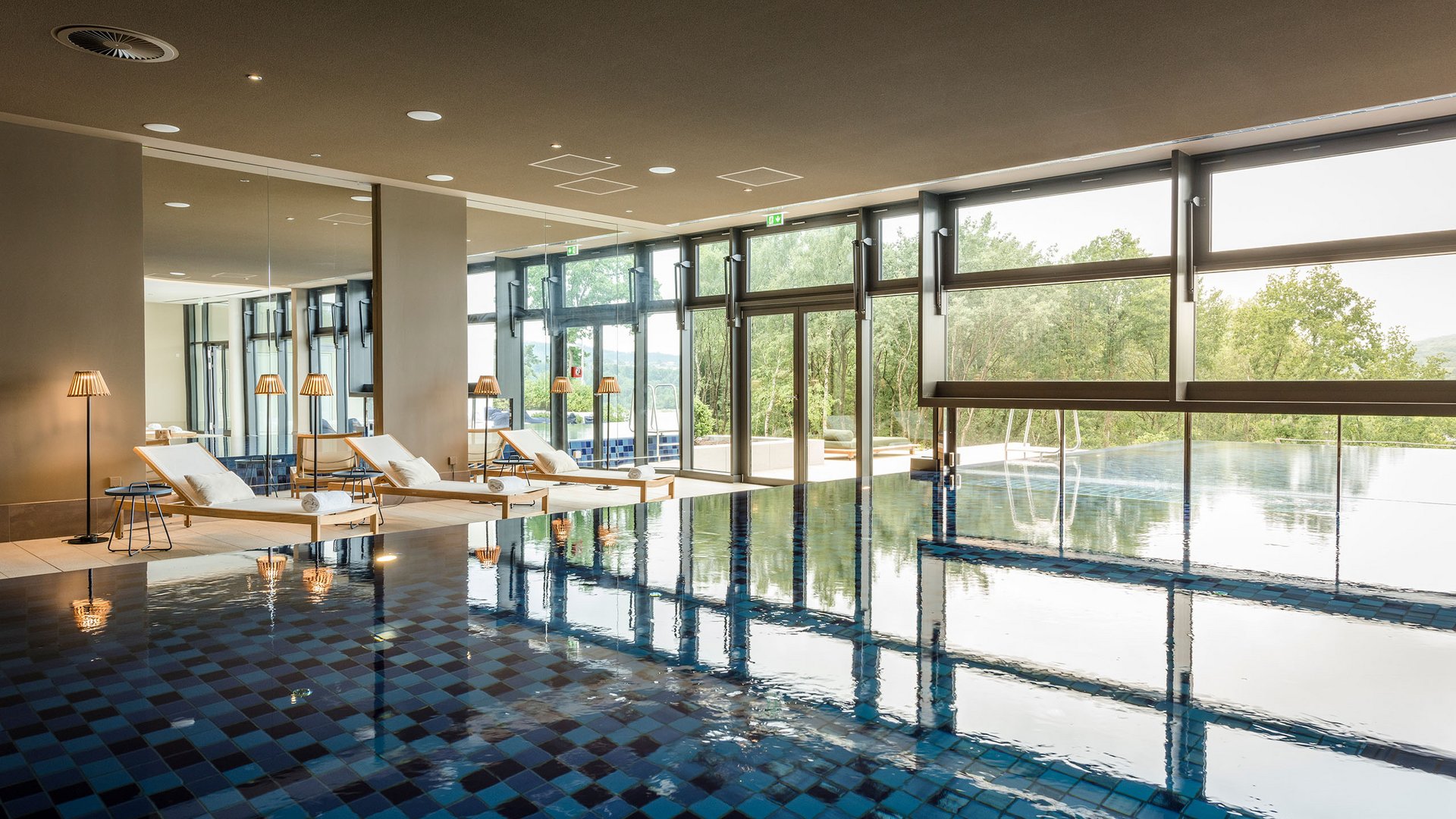 Seezeitlodge: Bildergalerie Innenpool mit Liegestühlen und großem Fenster mit Blick ins Grüne