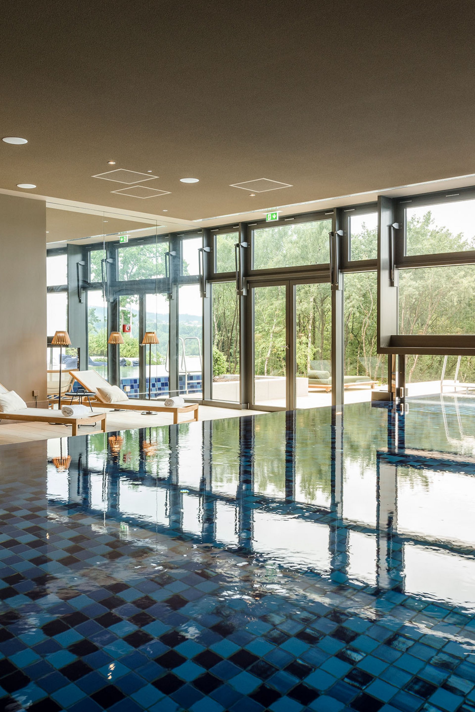 Seezeitlodge : Galerie photos Piscine intérieure avec chaises longues et grandes fenêtres donnant sur la nature