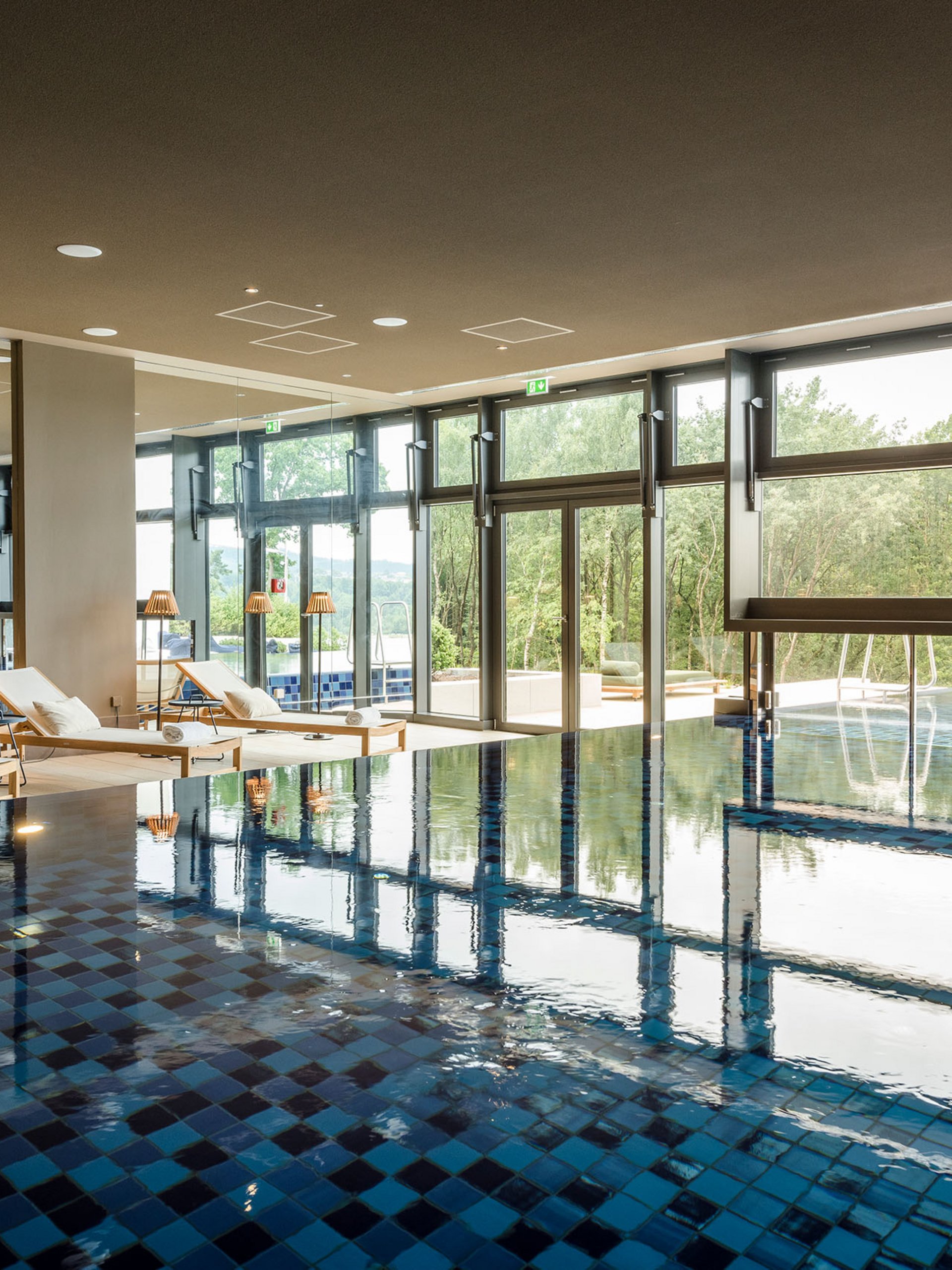 Seezeitlodge : Galerie photos Piscine intérieure avec chaises longues et grandes fenêtres donnant sur la nature