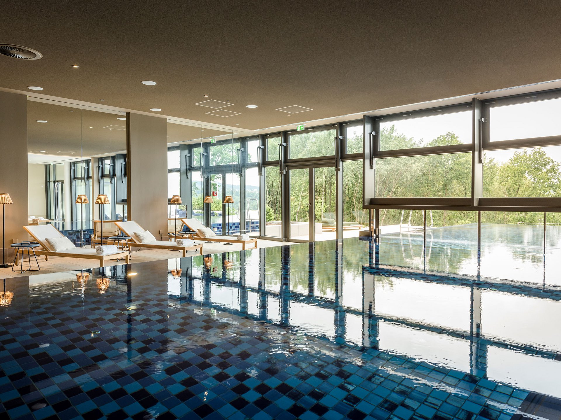 Seezeitlodge: Bildergalerie Innenpool mit Liegestühlen und großem Fenster mit Blick ins Grüne