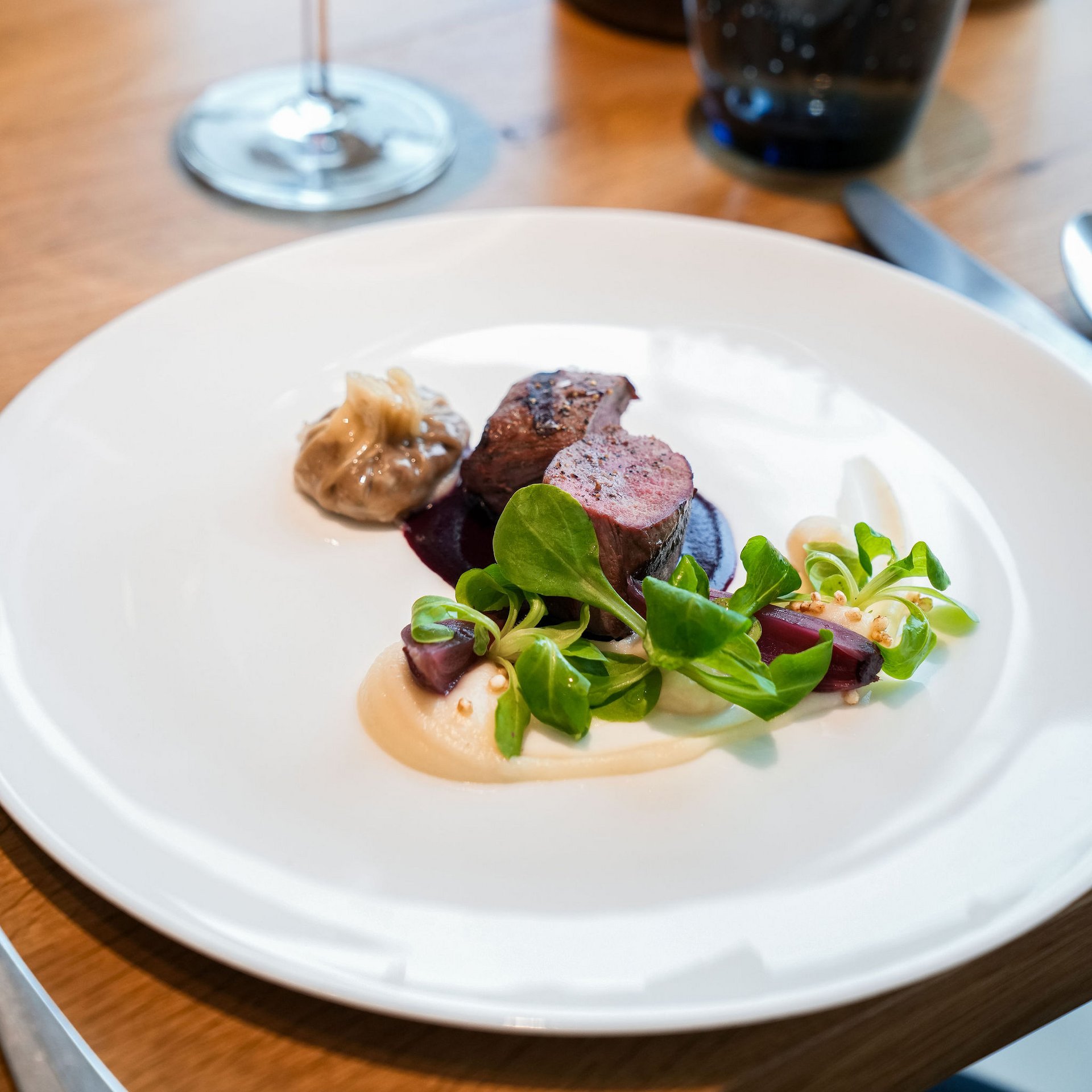 Seezeitlodge: your hotel at Lake Bostalsee Elegant dish with meat, sauce, green salad, and red wine in the background