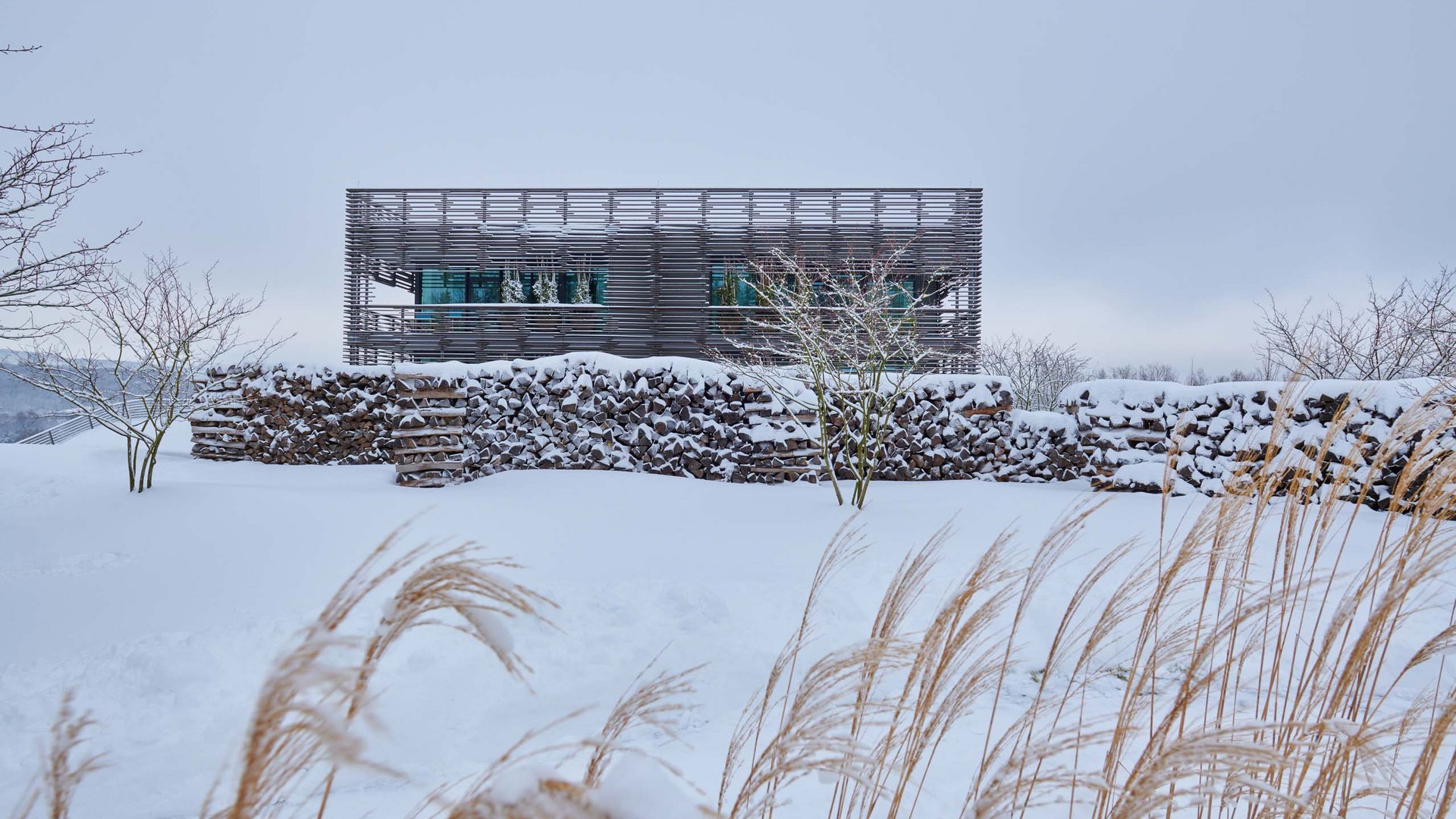 Die Seezeitlodge: Ihr Hotel am Bostalsee Modernes Gebäude hinter einer schneebedeckten Steinmauer in winterlicher Landschaft