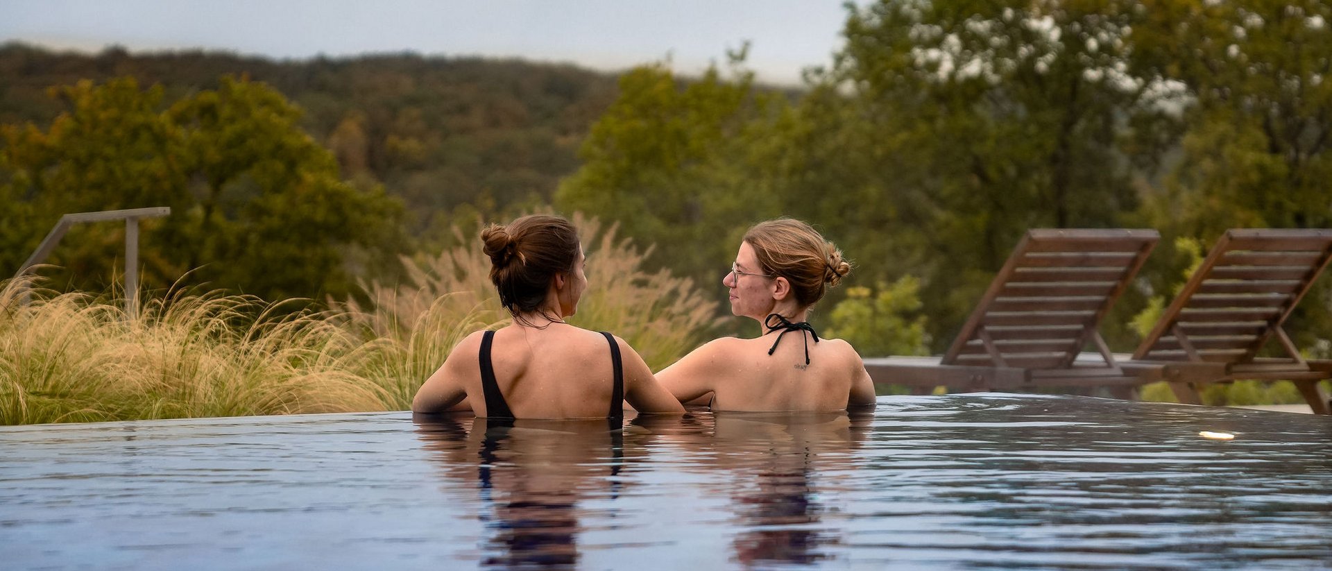 Seezeitlodge: Ihr Wellnesshotel am Bostalsee für pure Erholung Zwei Frauen im Pool mit Blick auf grüne Landschaft und Liegestühle