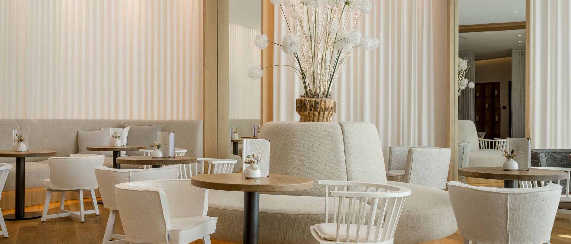 Seezeitlodge: Bildergalerie Helles, modernes Café mit weißen Möbeln und floraler Dekoration