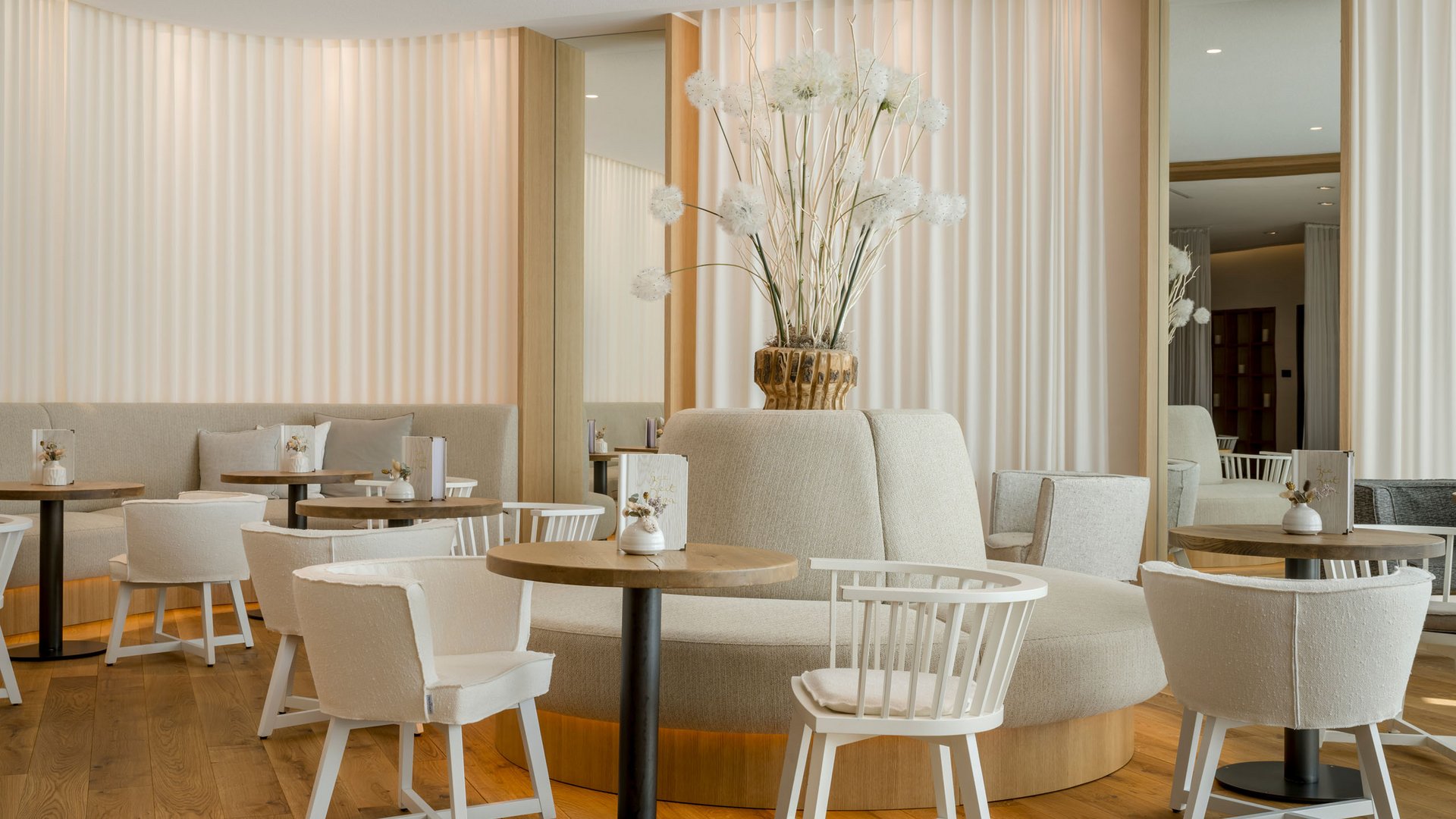 Seezeitlodge: Bildergalerie Helles, modernes Café mit weißen Möbeln und floraler Dekoration