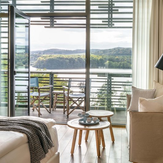 Luxushotel Seezeitlodge: Lassen Sie sich begeistern! Gemütliches Hotelzimmer mit Balkon und Blick auf See und Wald