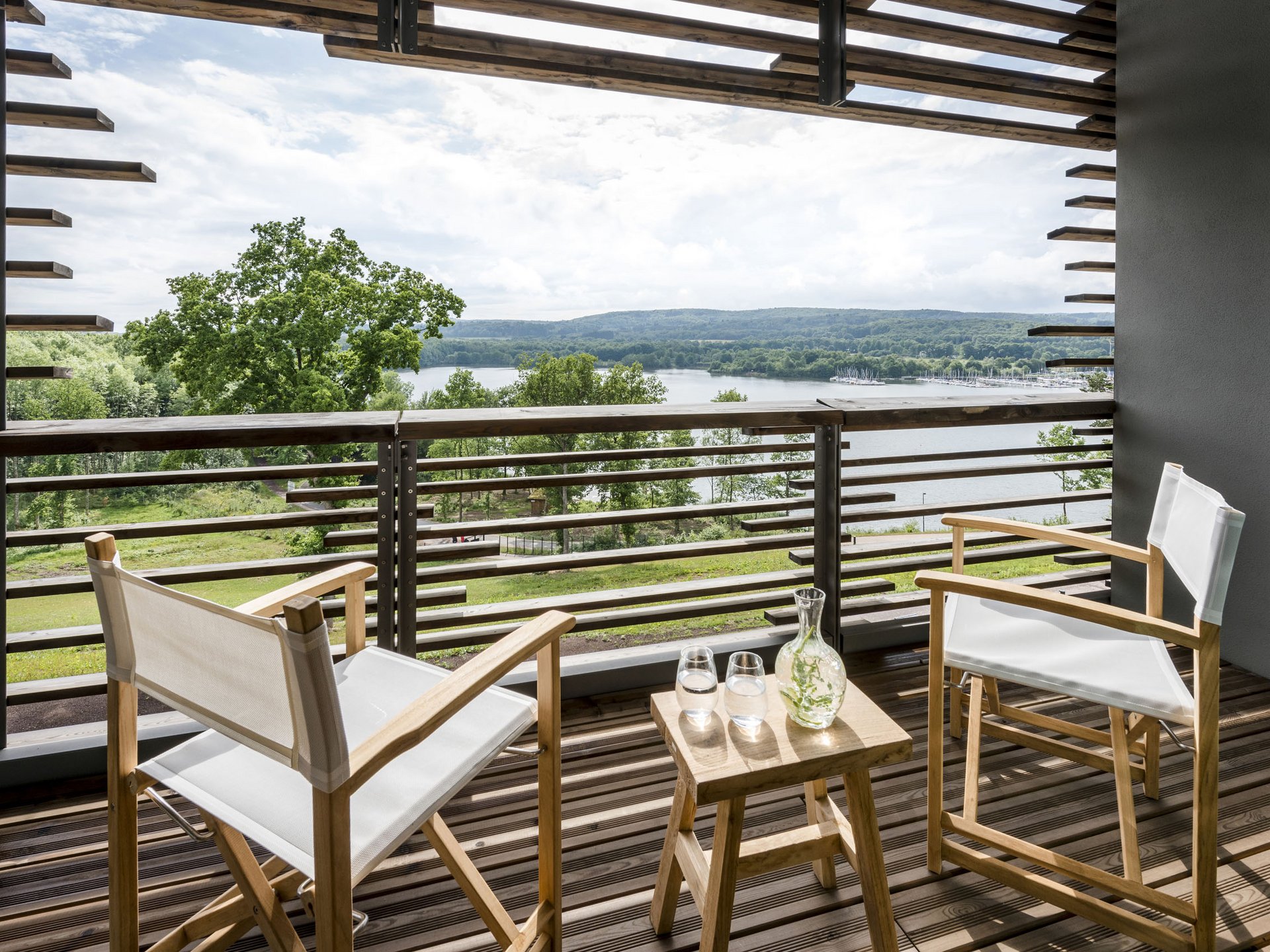 Design hotel Germany: your retreat at Lake Bostalsee Balcony with two chairs and table overlooking a lake and wooded hills