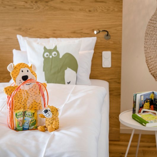 Übernachten am Bostalsee: Seezeitlodge Hotel & Spa Kinderzimmer mit Kuscheltieren, Bücher und Bett mit weißer Bettwäsche