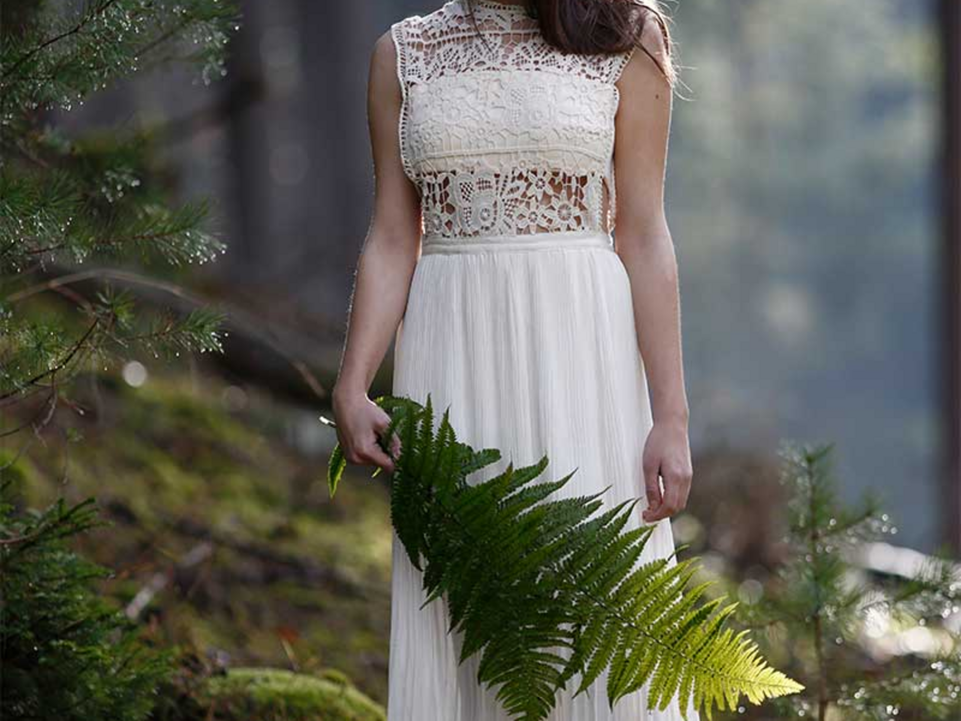 Litha - keltische Feiertage im Porträt | Seezeitlodge Hotel & Spa Frau in weißem Spitzenkleid hält Farnblatt in einem bewaldeten Gebiet