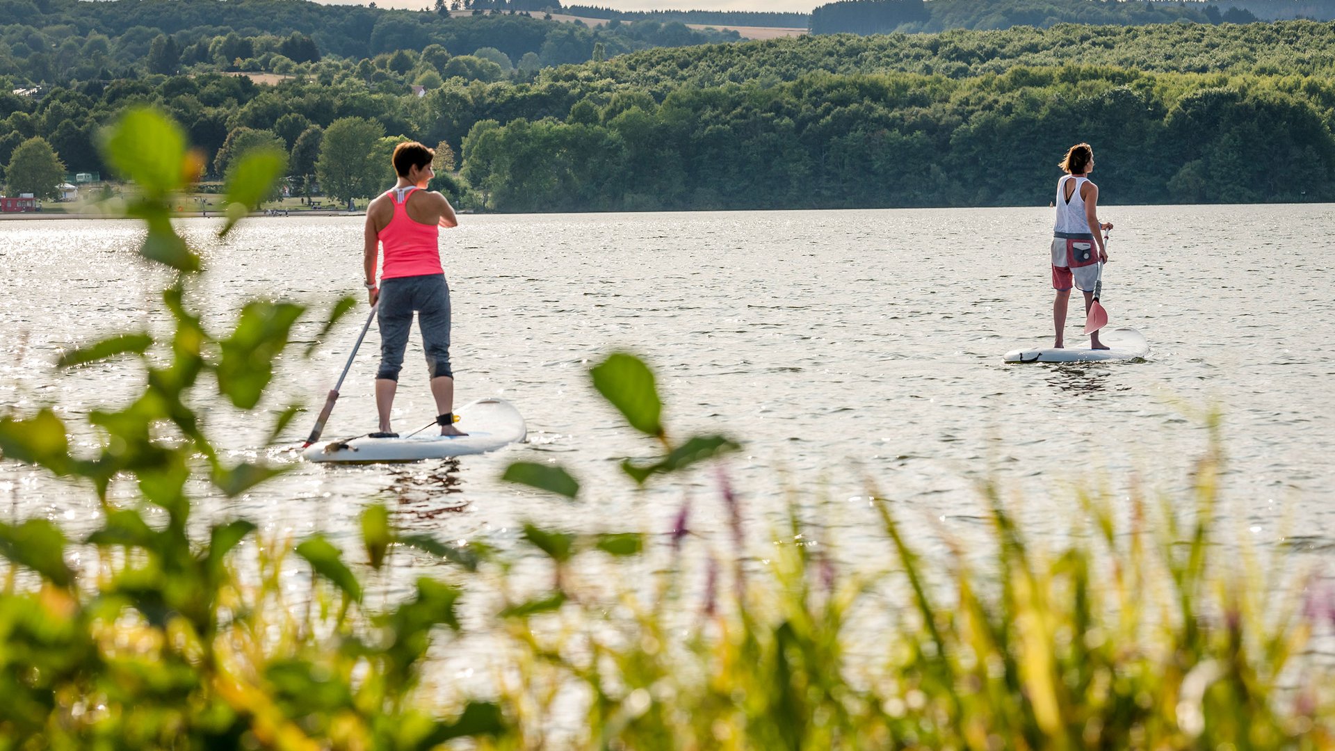 Seezeitlodge : Galerie photos Deux femmes en paddle sur un lac entouré de forêt