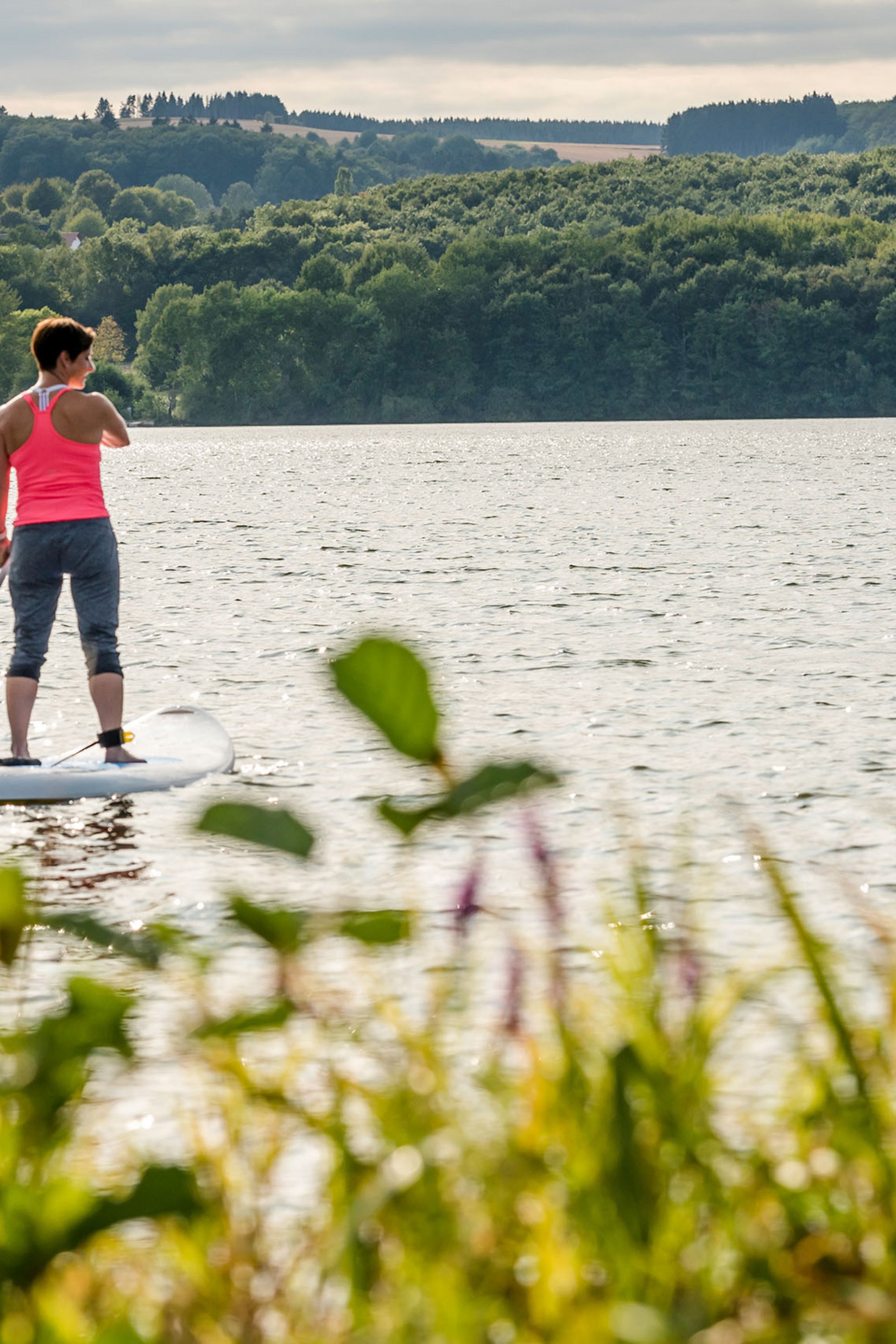 Seezeitlodge: Bildergalerie Zwei Frauen beim Stand-up-Paddling auf einem See umgeben von Wald