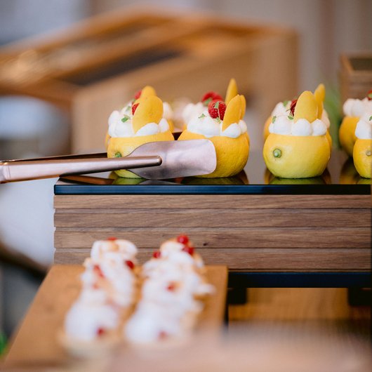 Seezeitlodge: Backstube und Patisserie Zitronen mit Sahne- und Fruchtfüllung als Dessert auf Display