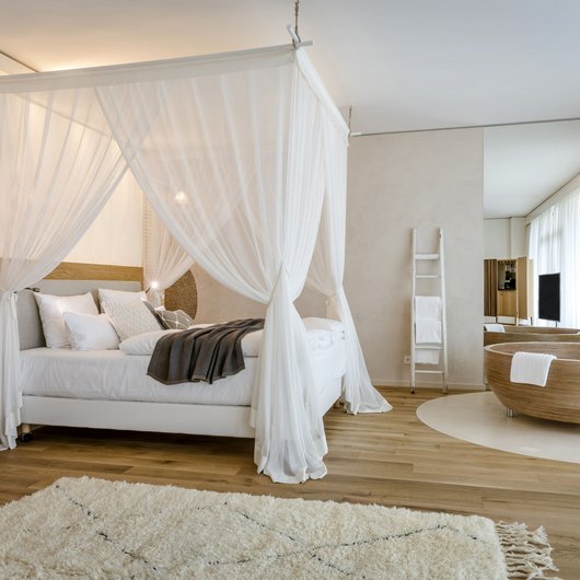 Übernachten am Bostalsee: Seezeitlodge Hotel & Spa Modernes Schlafzimmer mit Himmelbett und freistehender Badewanne in hellem Ambiente