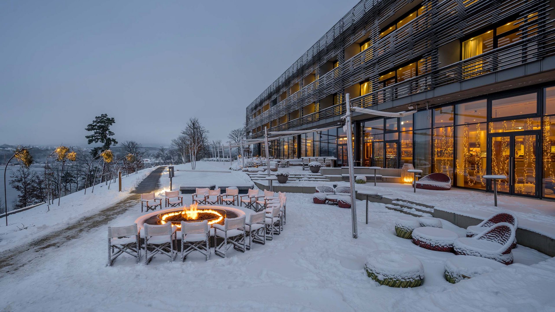 Die Seezeitlodge: Ihr Hotel am Bostalsee Modernes Hotel mit verschneiter Terrasse, Sitzgelegenheiten und leuchtender Feuerstelle