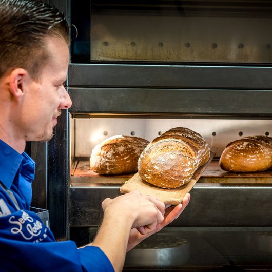 Ihr Genusshotel am Bostalsee Bäcker holt frisch gebackenes Brot aus dem Ofen