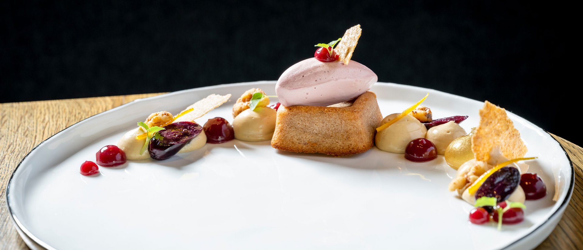 Seezeitlodge : Galerie photos Dessert élégant avec biscuit, glace et sauces fruitées sur assiette blanche